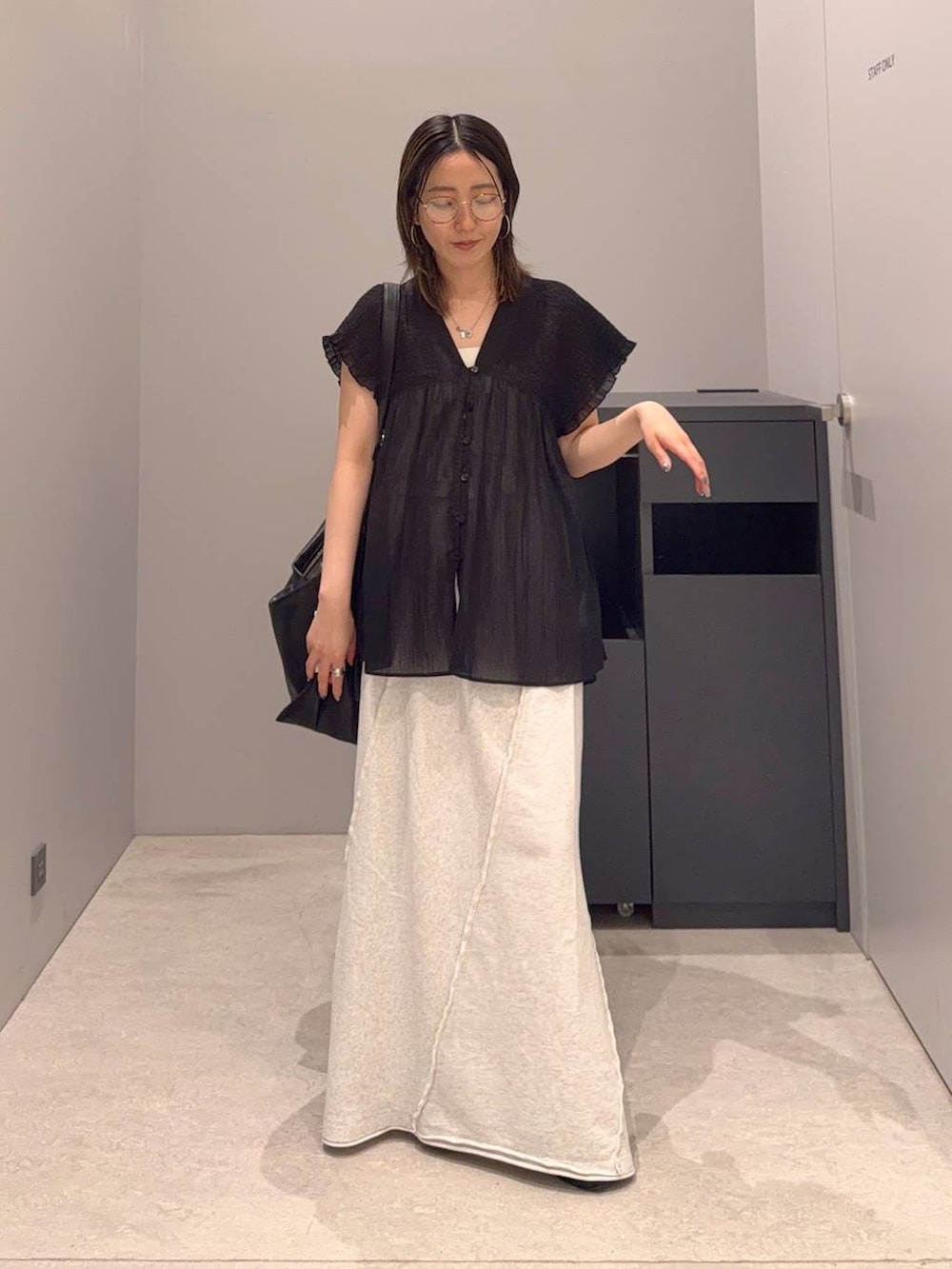 グレー系のスカート、ブラック系のショルダーバッグ、ブラック系のシャツ/ブラウスを着用したレディースの夏コーディネートの2枚目の写真