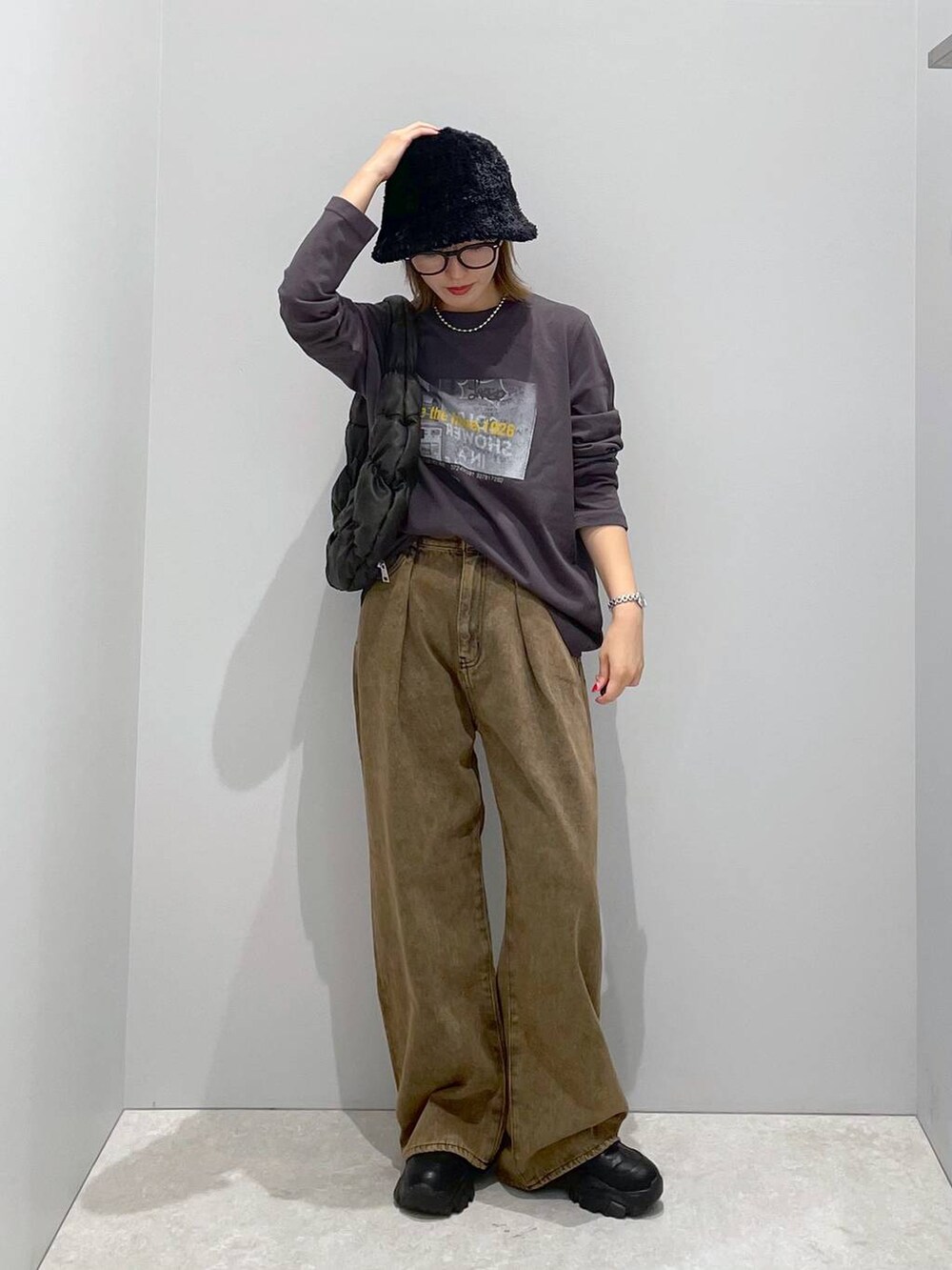ブラック系のハンドバッグ、ブラウン系のデニムパンツ、グレー系のTシャツ/カットソーを着用したレディースの秋コーディネートの4枚目の写真