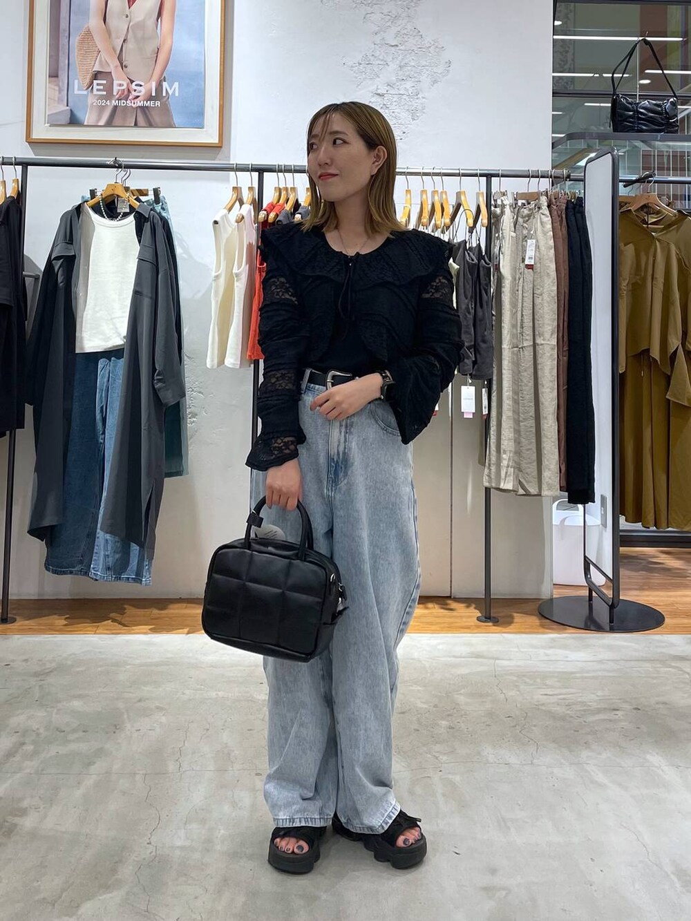 ブルー系のデニムパンツ、ブラック系のカーディガン/ボレロ、ブラック系のベルトを着用したレディースの夏コーディネートの2枚目の写真