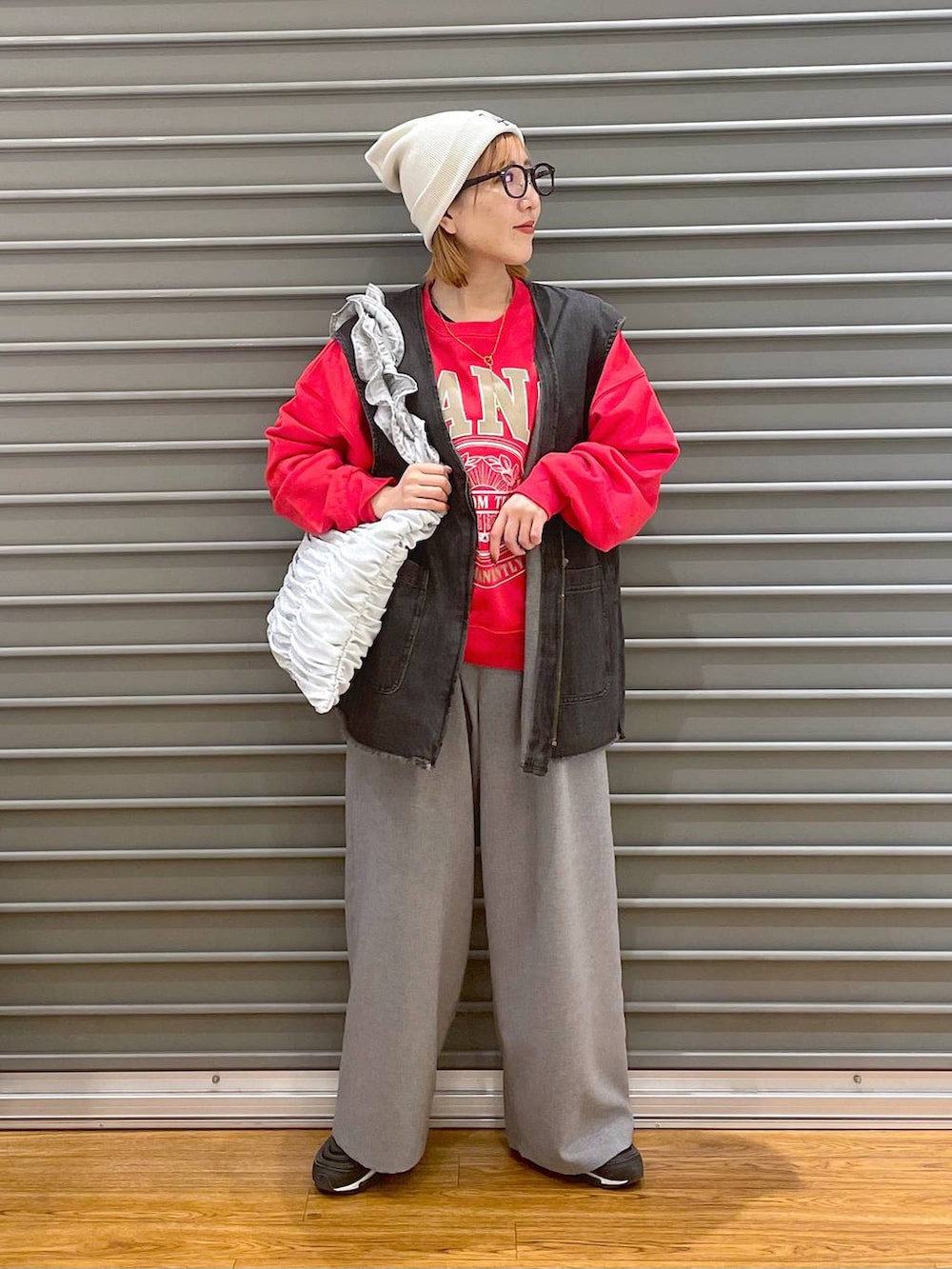 レッド系のスウェット、シルバー系のトートバッグ、グレー系のスラックスを着用したレディースの春コーディネートの3枚目の写真