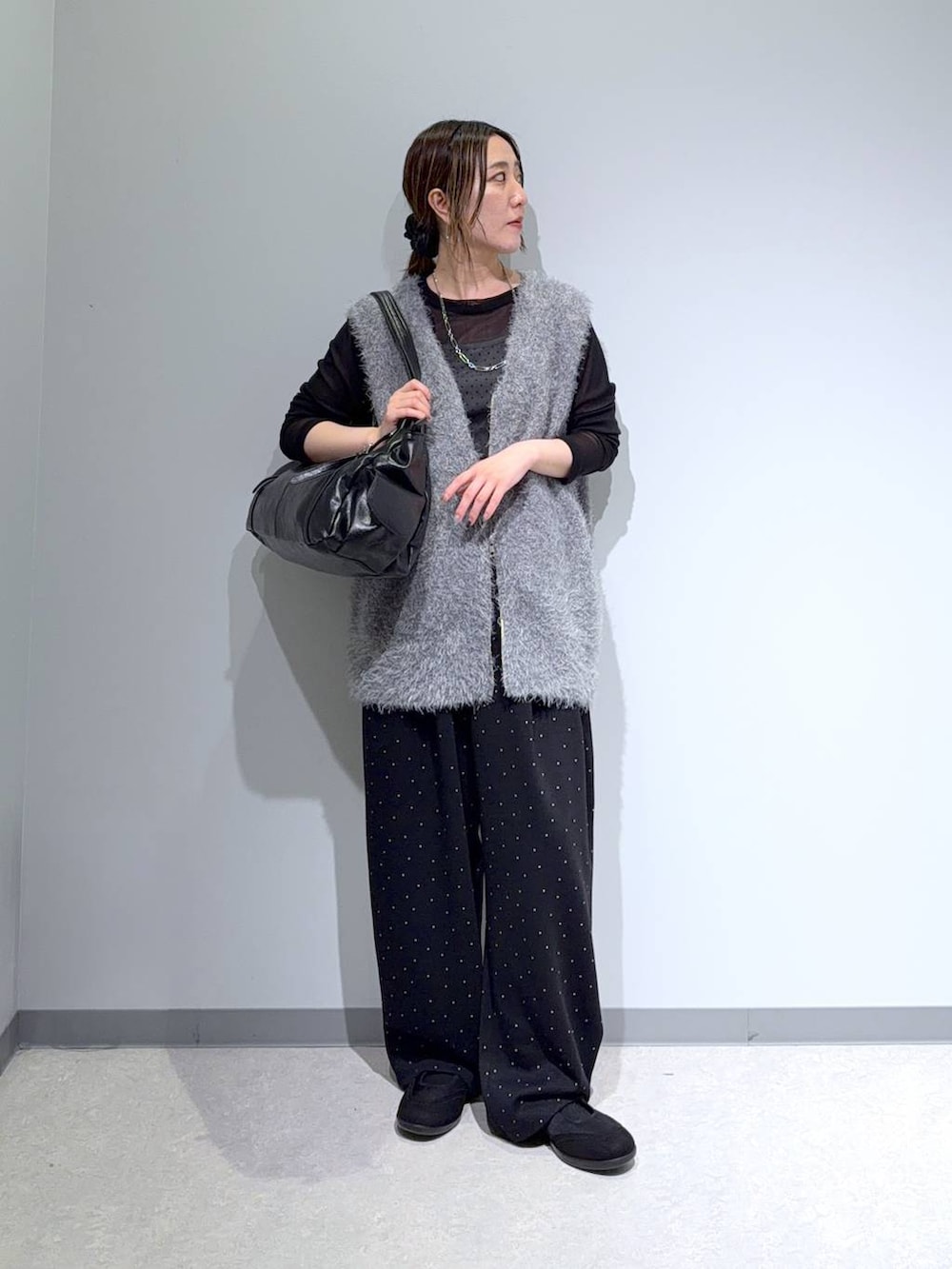 ブラック系のパンプス、ブラック系のトートバッグ、グレー系のベストを着用したレディースの秋コーディネートの2枚目の写真