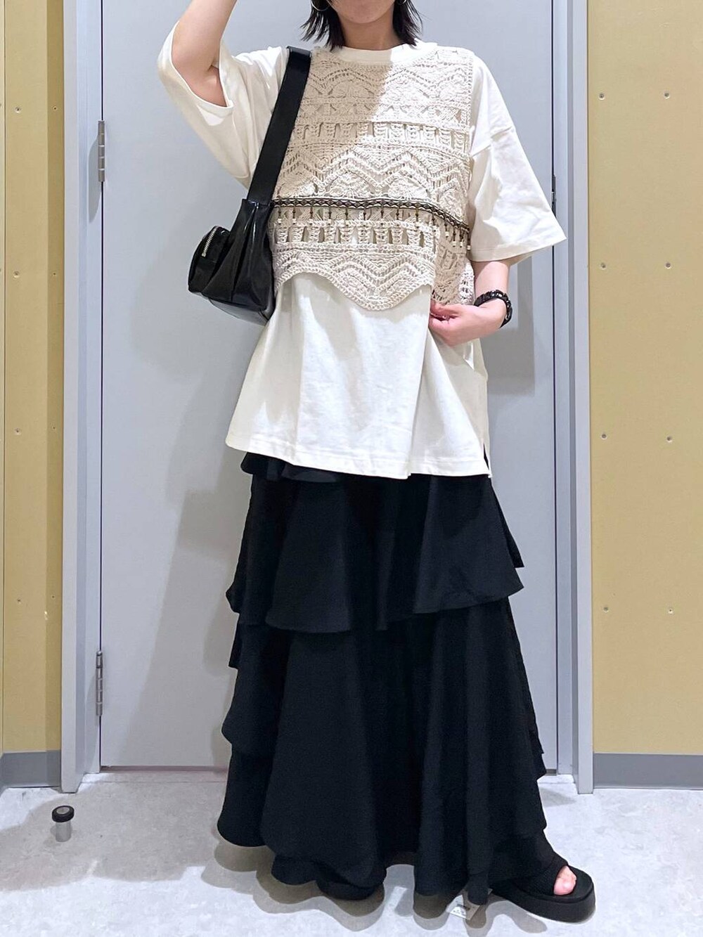 ブラック系のスカート、ブラック系のショルダーバッグ、ブラック系のサンダルを着用したレディースの春コーディネートの3枚目の写真