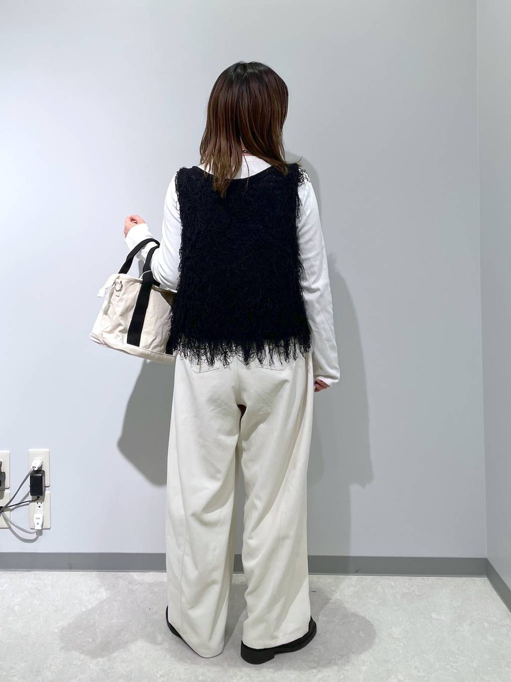 ホワイト系のトートバッグ、ホワイト系のその他パンツ、ブラック系のベストを着用したレディースの春コーディネートの2枚目の写真