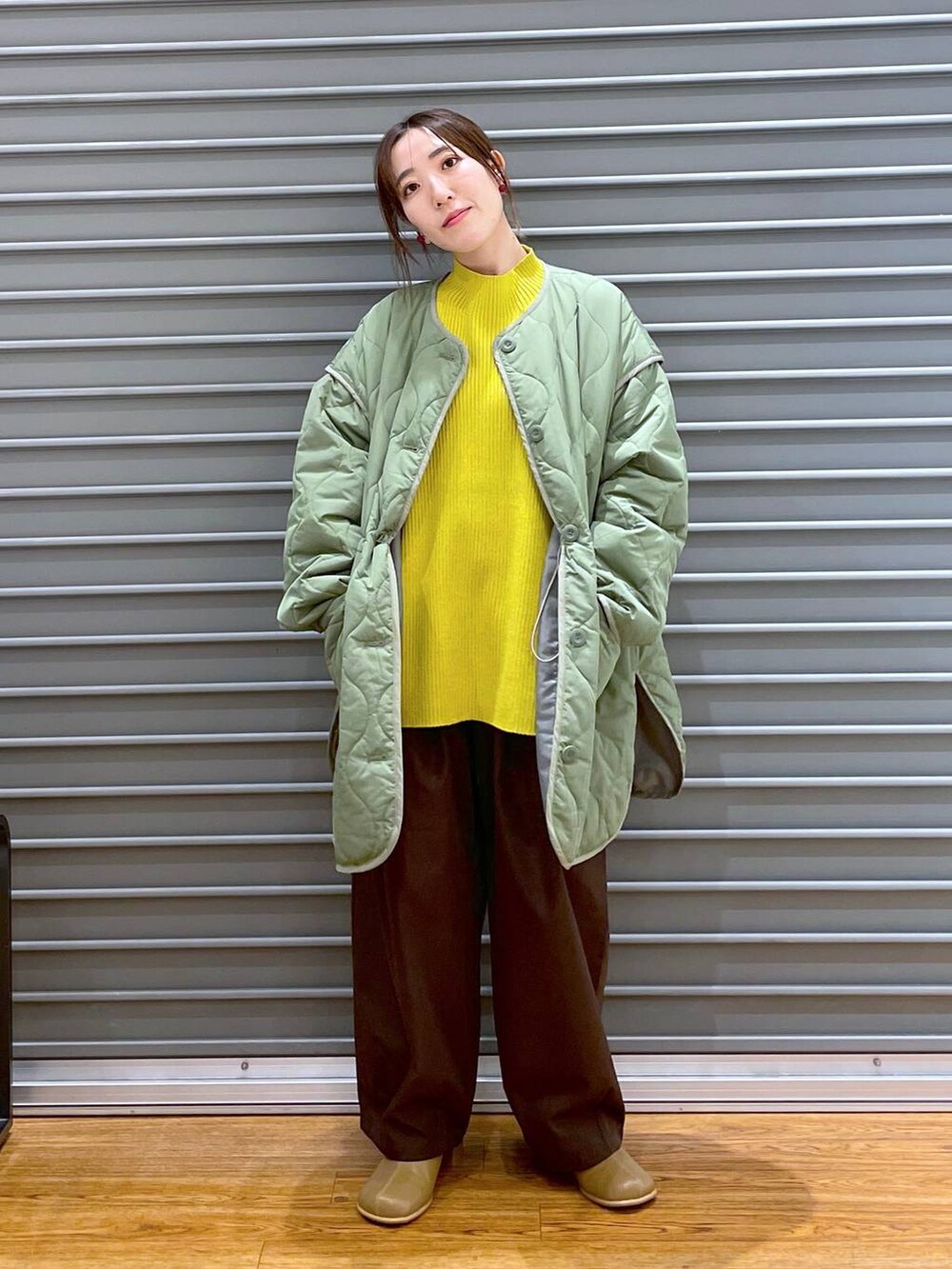 イエロー系のニット/セーター、グリーン系のその他アウター、ブラウン系のブーツを着用したレディースの秋コーディネートの2枚目の写真