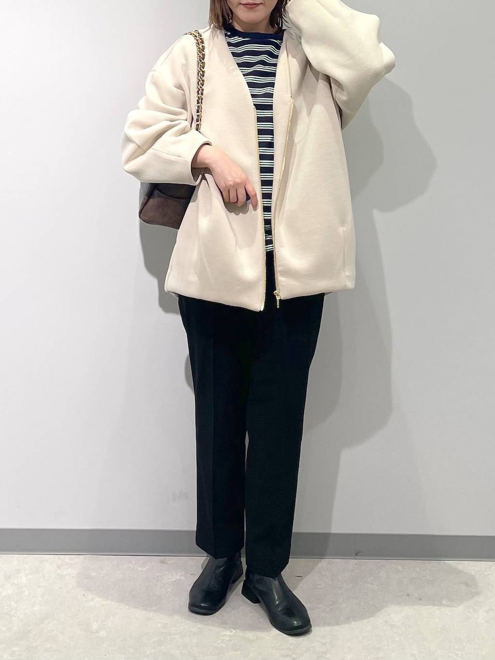 ホワイト系のブルゾン、ブラック系のスラックス、ブラウン系のショルダーバッグを着用したレディースの春コーディネートの5枚目の写真