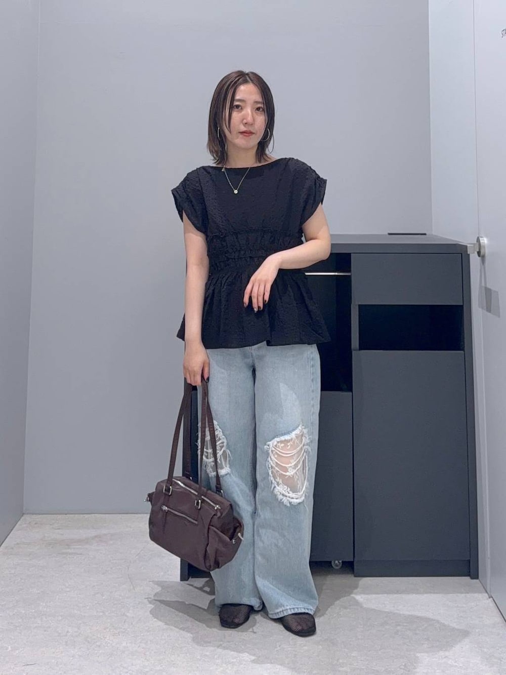 ブルー系のデニムパンツ、ブラック系のシャツ/ブラウス、ブラウン系のボストンバッグを着用したレディースの夏コーディネートの3枚目の写真