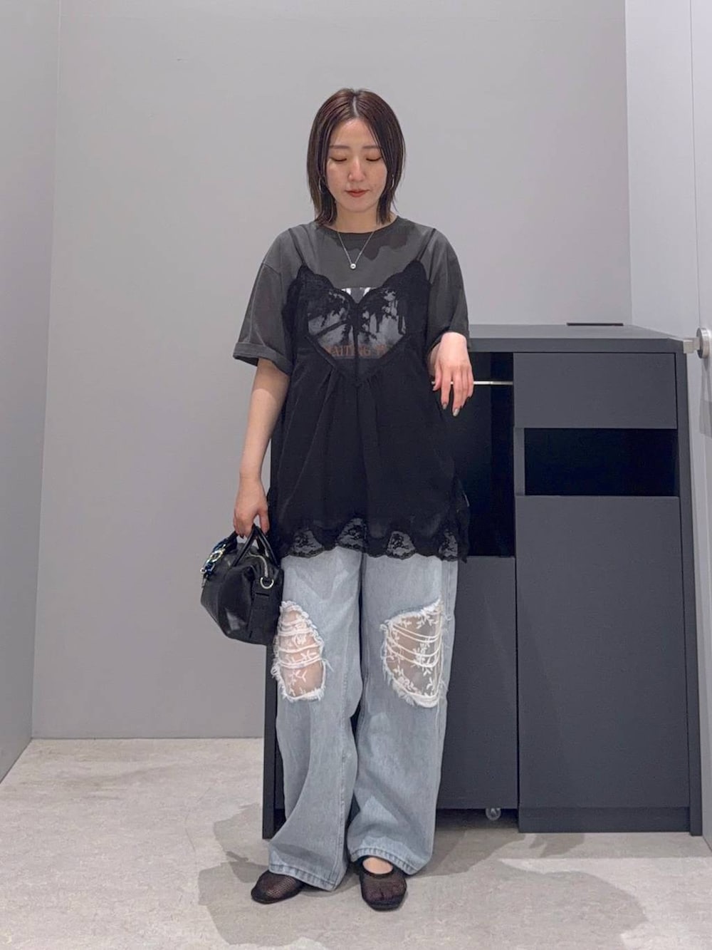ブルー系のデニムパンツ、ブラック系のボストンバッグを着用したレディースの夏コーディネートの2枚目の写真