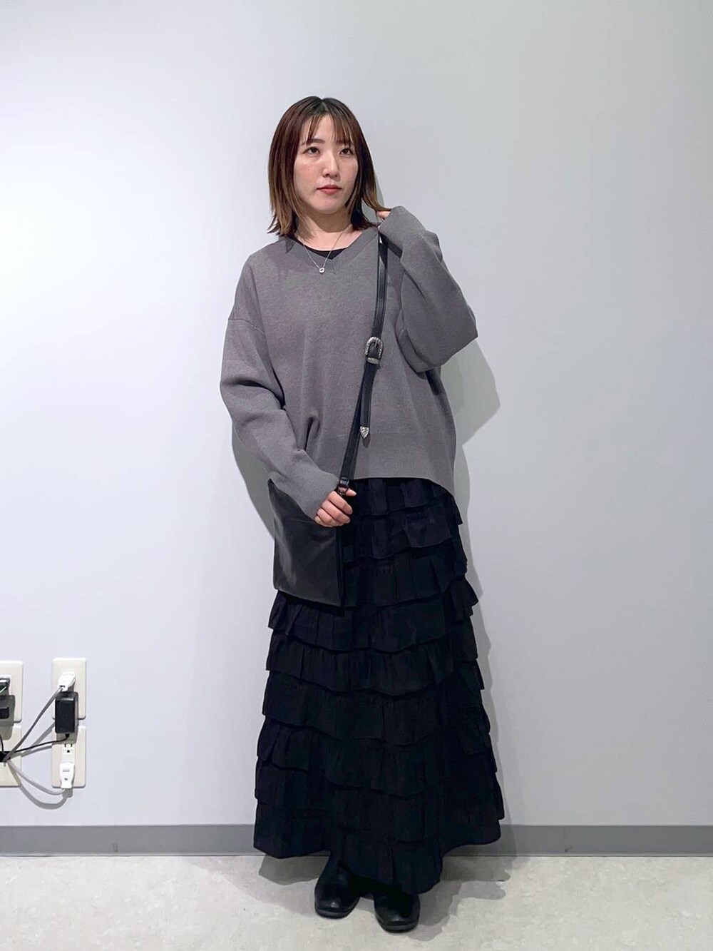 グレー系のスウェット、ブラック系のスカート、ブラック系のショルダーバッグを着用したレディースの冬コーディネートの2枚目の写真