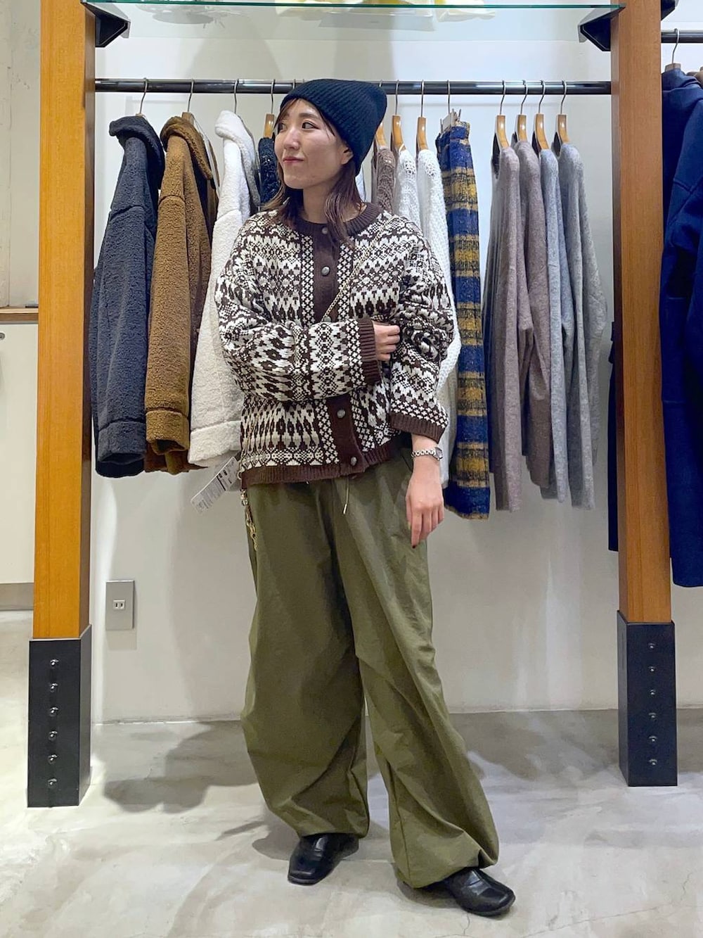 グリーン系のその他パンツ、ブラウン系のカーディガン/ボレロ、ベージュ系のスマホグッズを着用したレディースの冬コーディネートの2枚目の写真