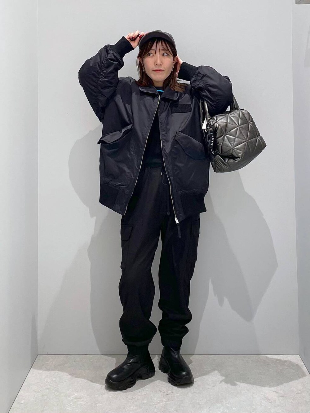 ブラック系のブルゾン、ブラック系のトートバッグ、ブラック系のカーゴパンツを着用したレディースの冬コーディネートの6枚目の写真