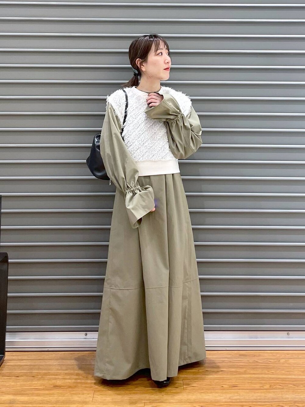 ホワイト系のベスト、ブラック系のパンプス、グリーン系のワンピースを着用したレディースの春コーディネートの4枚目の写真