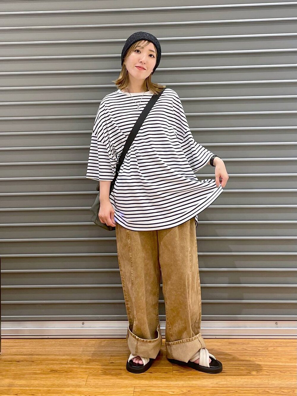 ブラック系のショルダーバッグ、ホワイト系のサンダル、ホワイト系のTシャツ/カットソーを着用したレディースの夏コーディネートの2枚目の写真