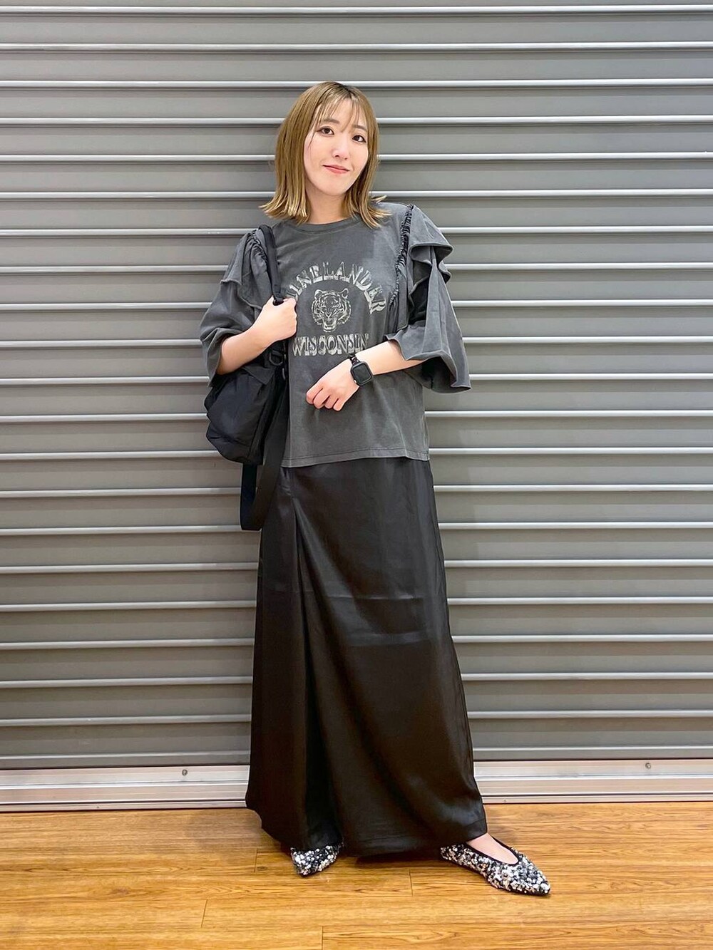 ブラック系のショルダーバッグ、シルバー系のパンプス、ブラック系のスカートを着用したレディースの夏コーディネートの2枚目の写真