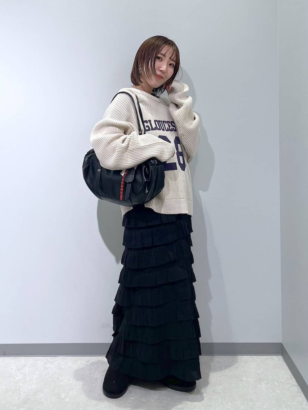 ブラック系のスカート、ブラック系のブーツ、ブラック系のボストンバッグを着用したレディースの冬コーディネートの3枚目の写真