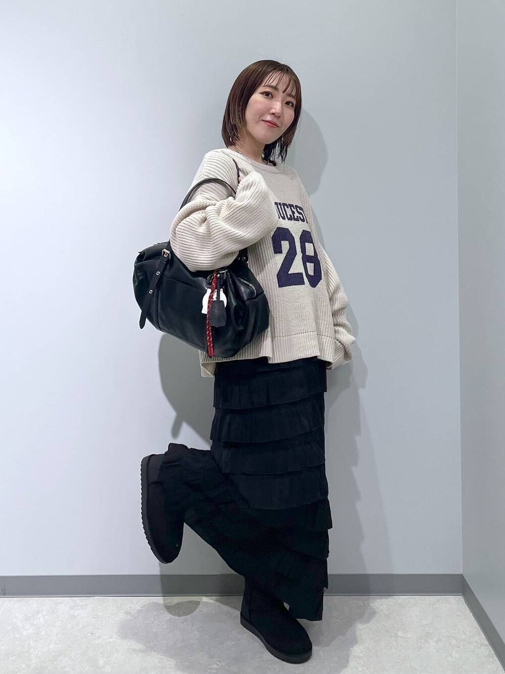 ブラック系のスカート、ブラック系のブーツ、ブラック系のボストンバッグを着用したレディースの冬コーディネートの2枚目の写真