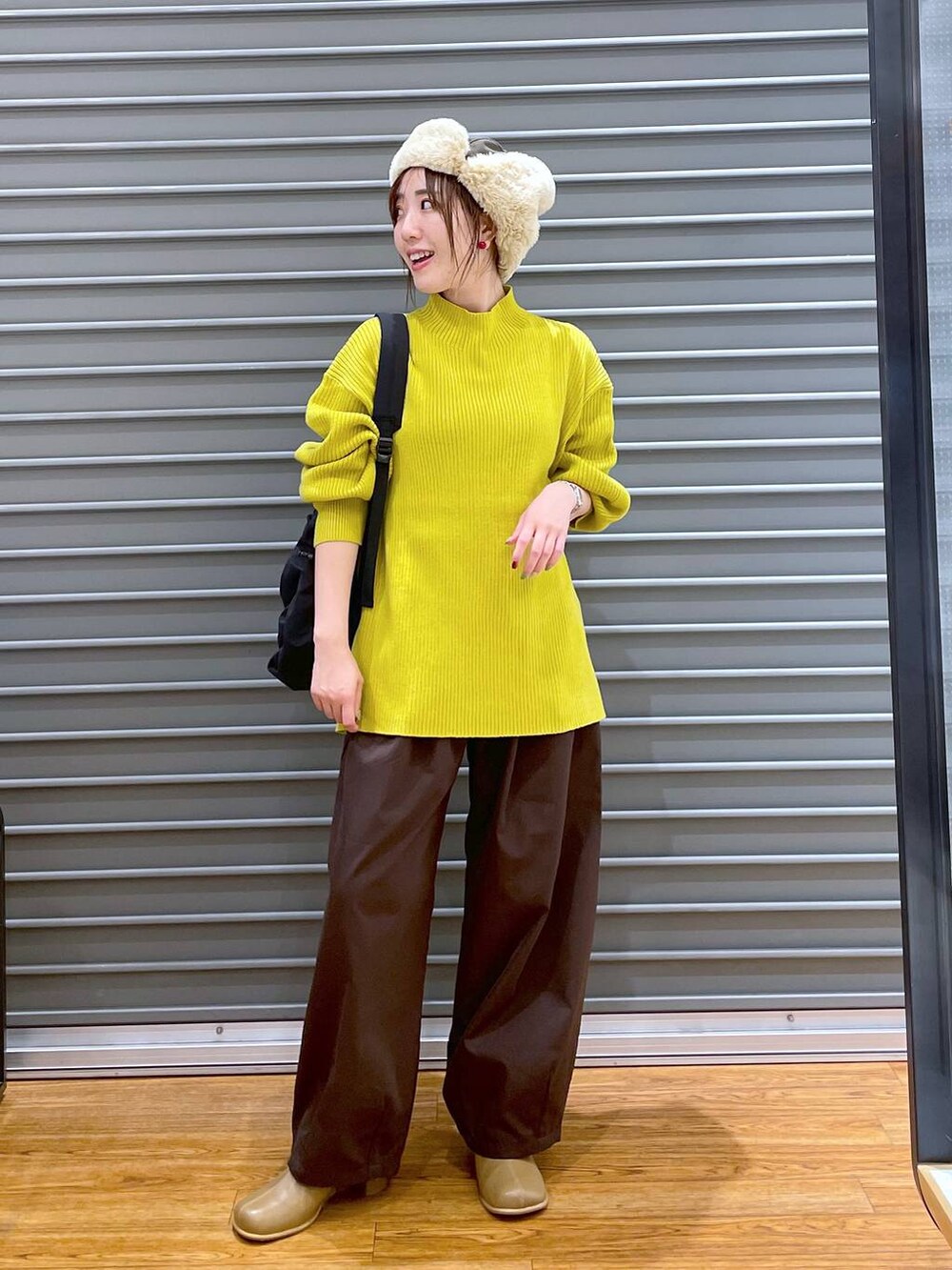 イエロー系のニット/セーター、ブラウン系のブーツ、ブラウン系のその他パンツを着用したレディースの冬コーディネートの2枚目の写真