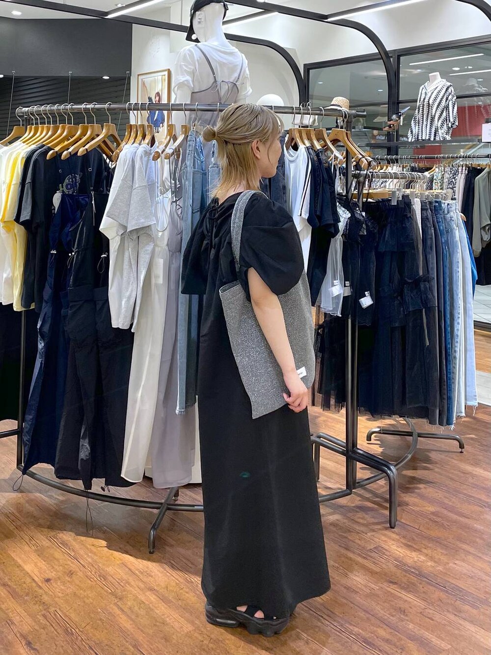 シルバー系のトートバッグ、ブラック系のワンピースを着用したレディースの夏コーディネートの2枚目の写真