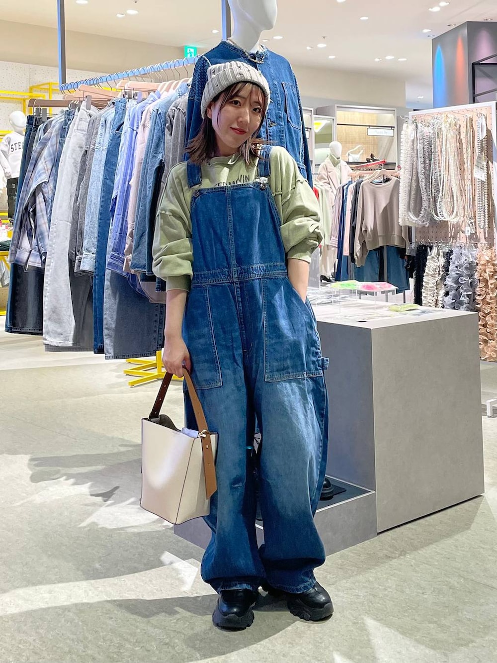 ブルー系のサロペット/オーバーオール、ホワイト系のショルダーバッグ、グリーン系のスウェットを着用したレディースの冬コーディネートの2枚目の写真