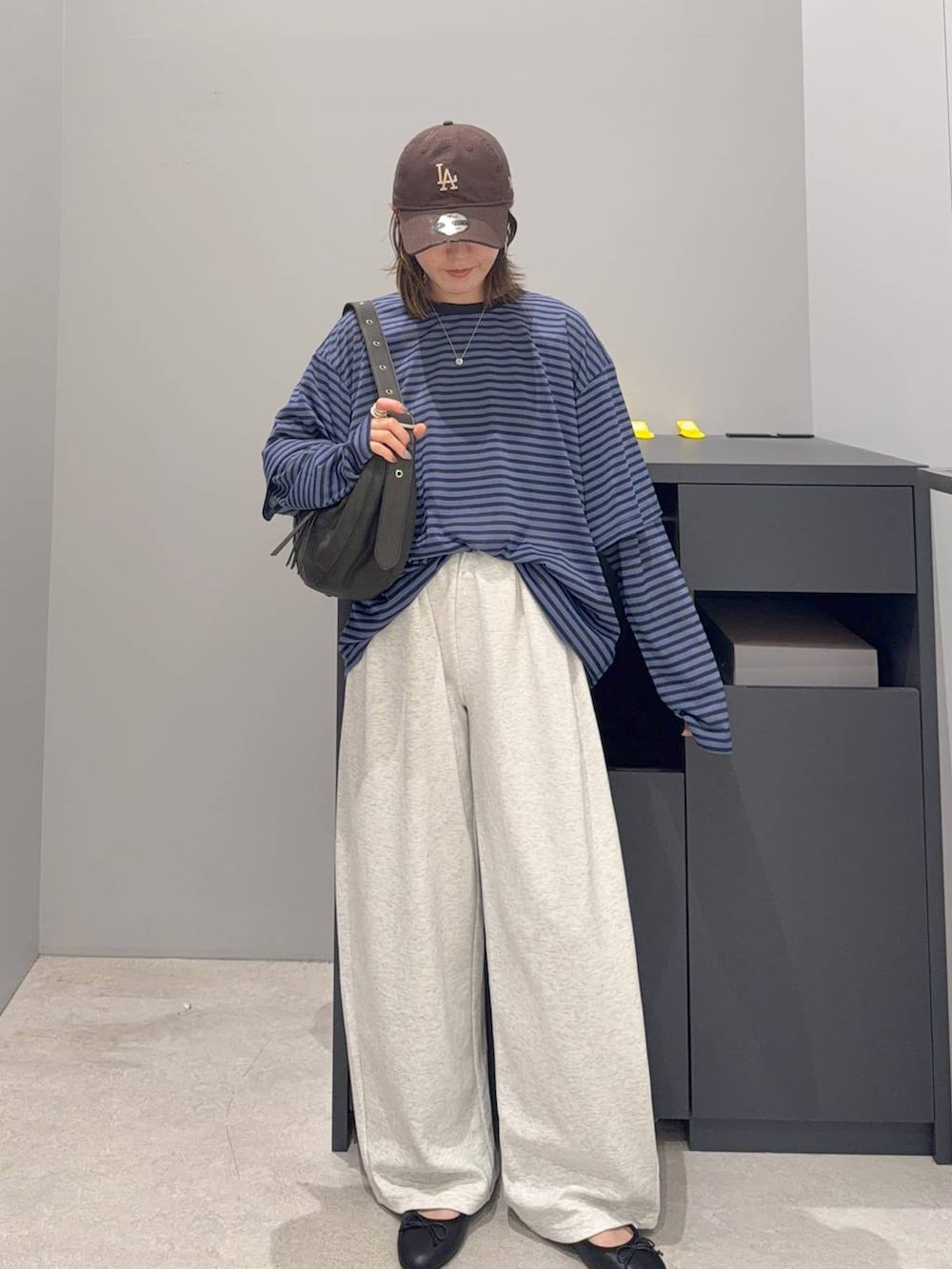 ブラック系のショルダーバッグ、ブルー系のTシャツ/カットソー、ベージュ系のスウェットパンツを着用したレディースの夏コーディネートの2枚目の写真