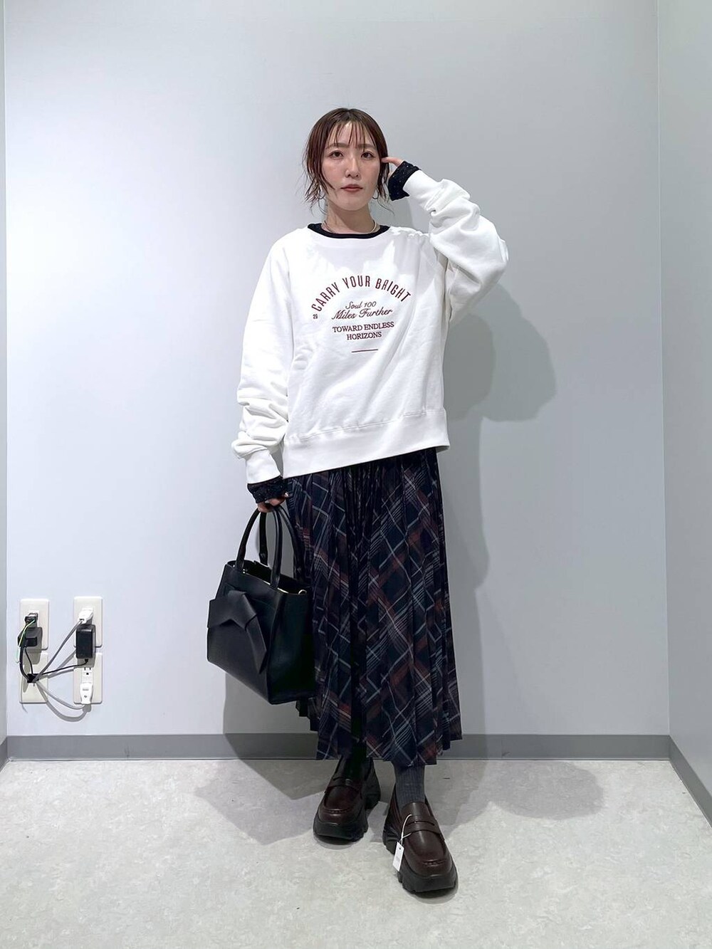 ブルー系のスカート、ブラック系のハンドバッグ、ブラック系のTシャツ/カットソーを着用したレディースの冬コーディネートの2枚目の写真