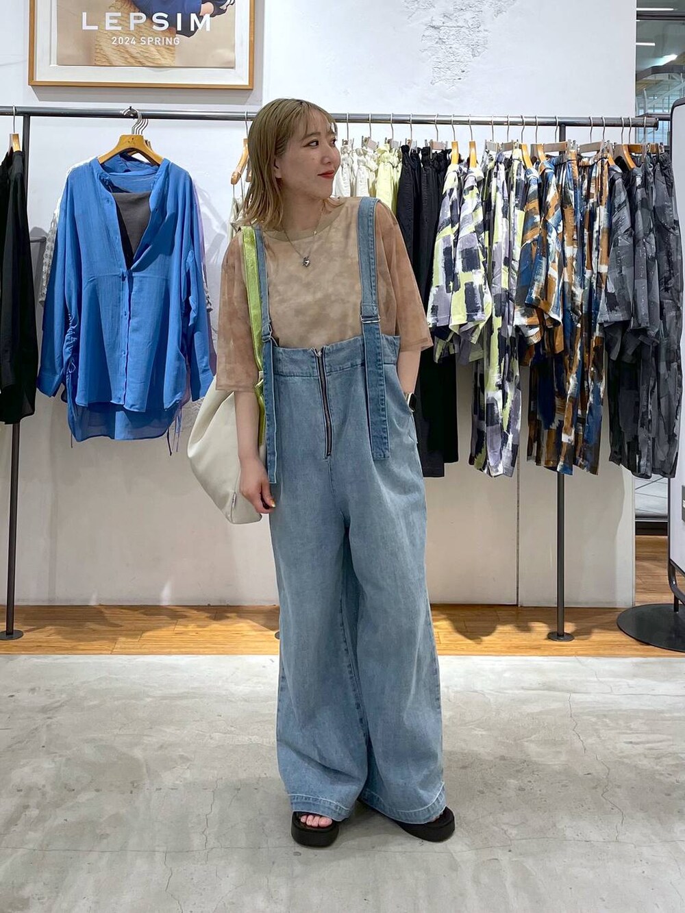 ブラウン系のTシャツ/カットソー、ブルー系のデニムパンツ、ホワイト系のショルダーバッグを着用したレディースの春コーディネートの2枚目の写真