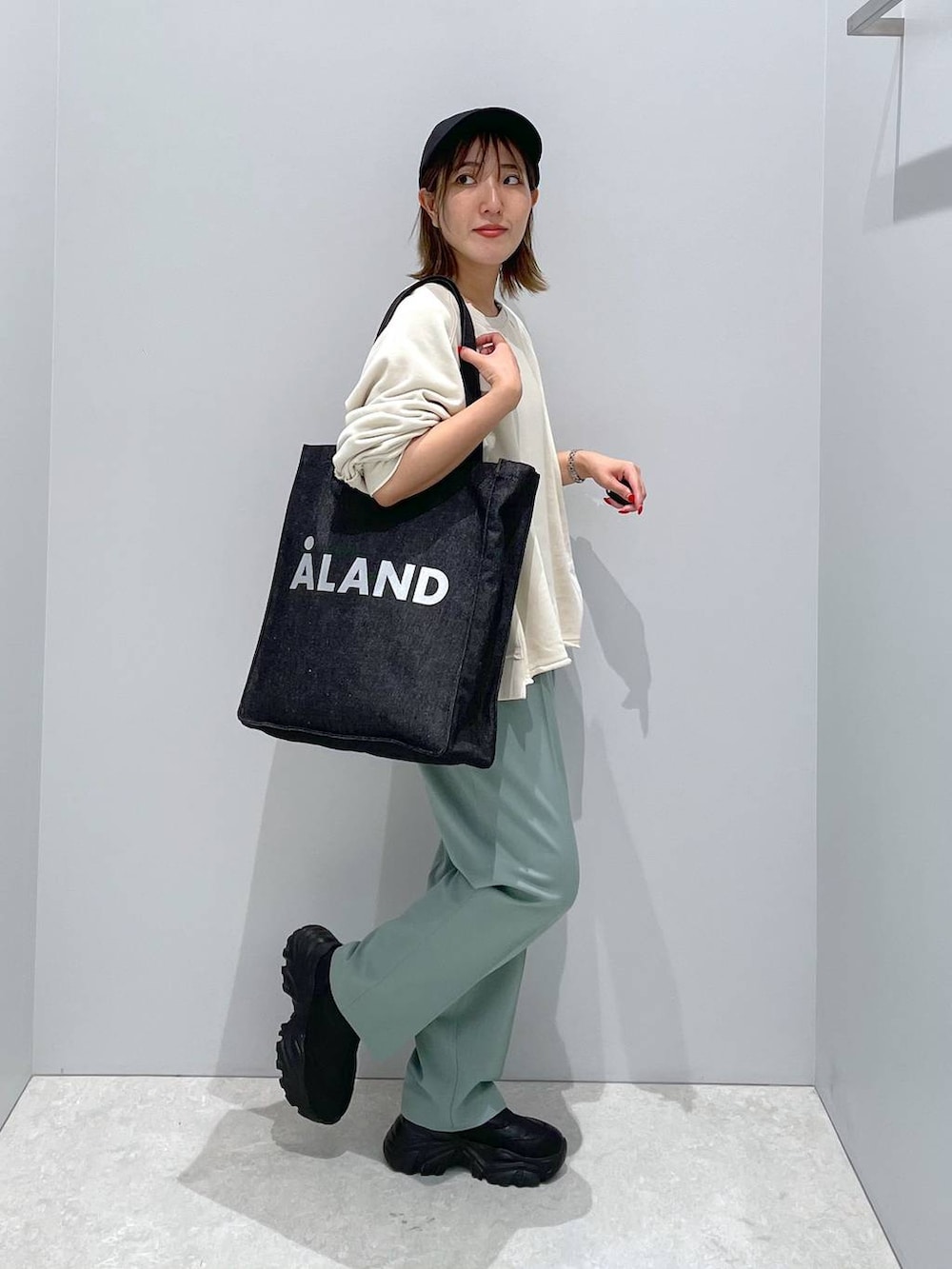 ブラック系のトートバッグ、グリーン系のその他パンツ、ベージュ系のTシャツ/カットソーを着用したレディースの秋コーディネートの3枚目の写真