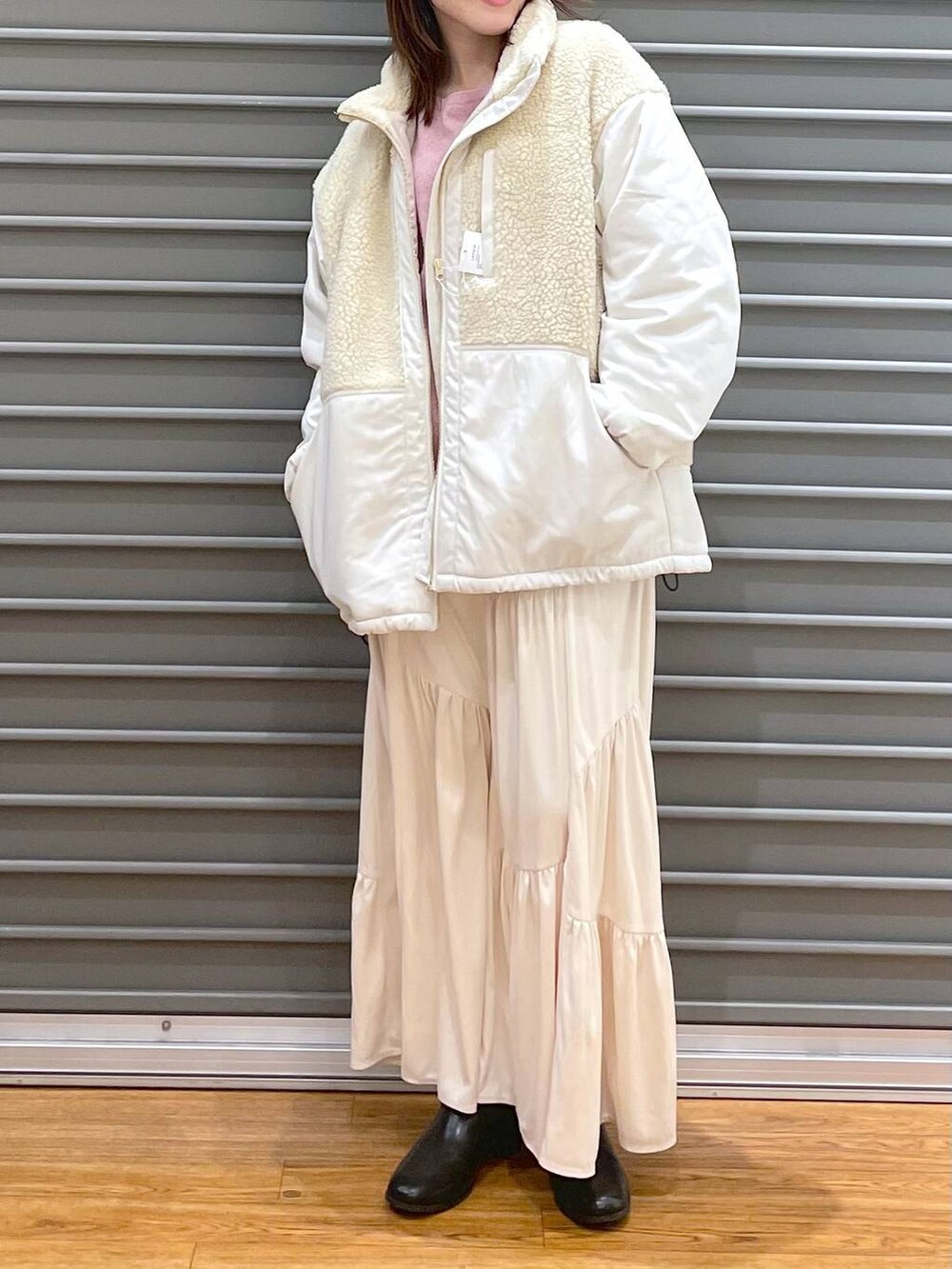 ピンク系のニット/セーター、ホワイト系のその他アウター、ブラウン系のブーツを着用したレディースの冬コーディネートの2枚目の写真