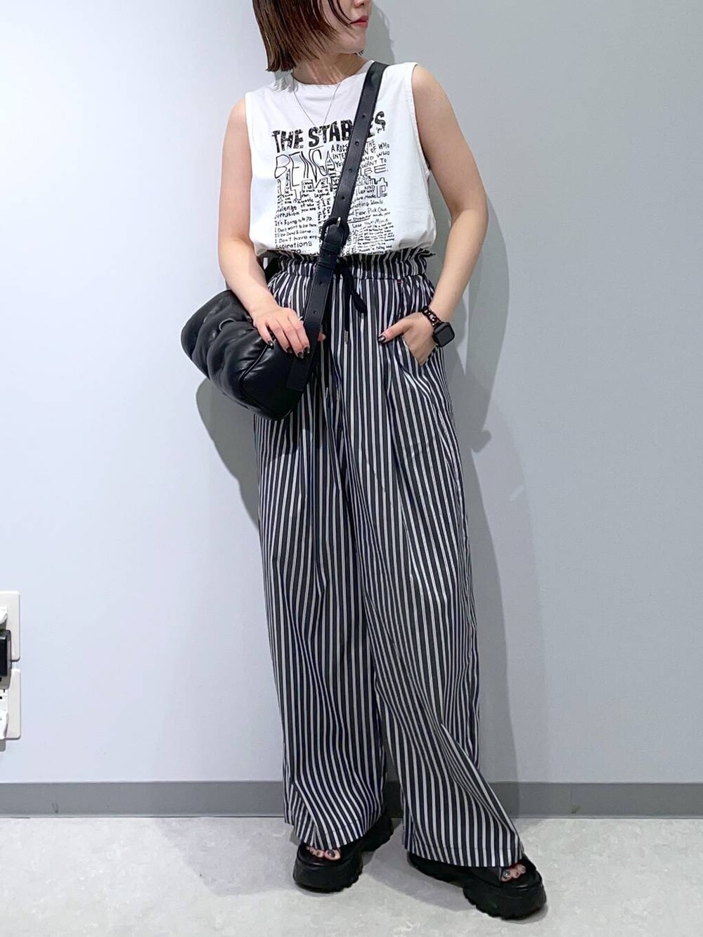 ブラック系のサンダル、ブラック系のショルダーバッグ、ホワイト系のTシャツ/カットソーを着用したレディースの夏コーディネートの2枚目の写真