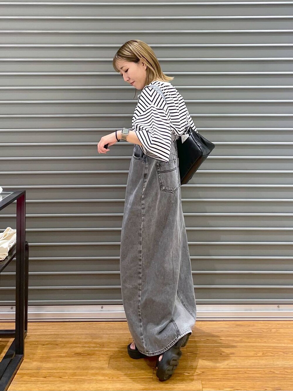 ブラック系のショルダーバッグ、ホワイト系のTシャツ/カットソー、グレー系のジャンパースカートを着用したレディースの夏コーディネートの2枚目の写真