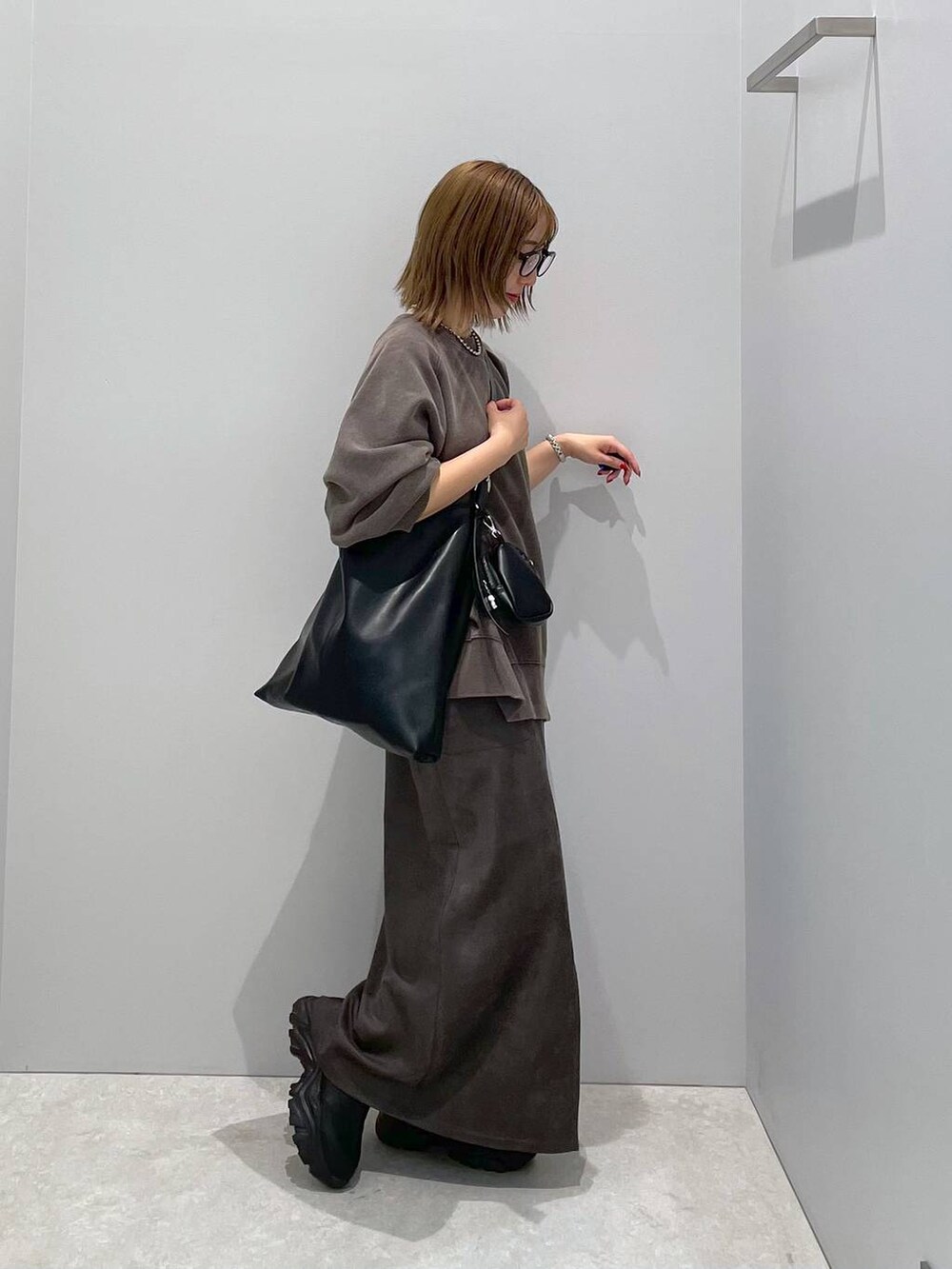 ブラック系のショルダーバッグ、ブラック系のスウェット、グレー系のスカートを着用したレディースの秋コーディネートの4枚目の写真