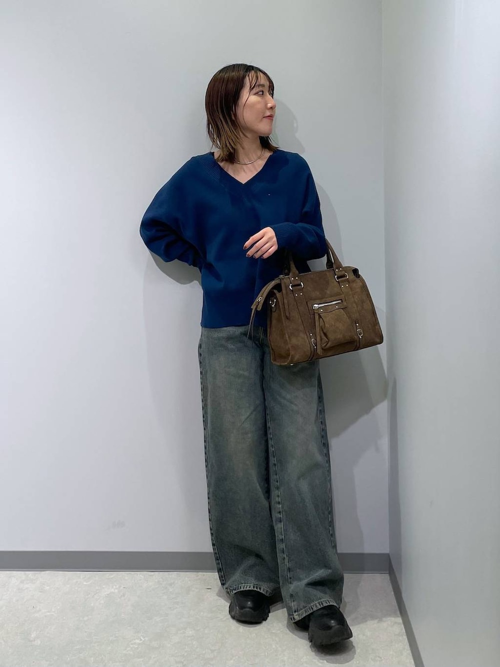 ブラウン系のボストンバッグ、ブルー系のニット/セーター、ブルー系のデニムパンツを着用したレディースの冬コーディネートの3枚目の写真