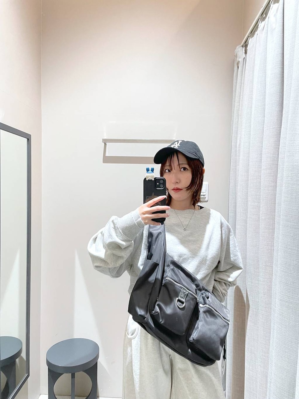 グレー系のショルダーバッグ、グレー系のスウェット、ベージュ系のスウェットパンツを着用したレディースの冬コーディネートの2枚目の写真