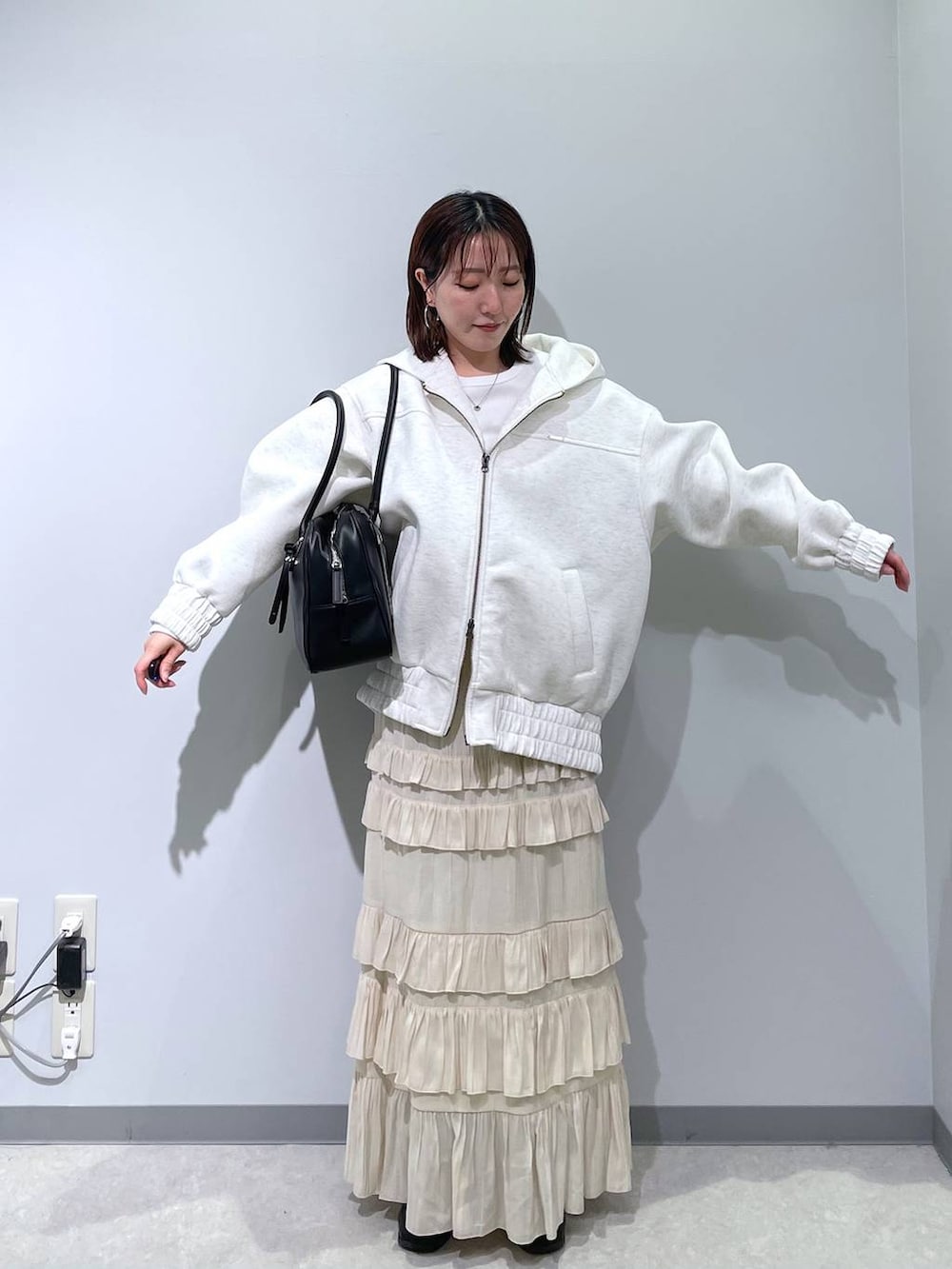 ブラック系のボストンバッグ、ベージュ系のブルゾン、ホワイト系のスカートを着用したレディースの春コーディネートの4枚目の写真