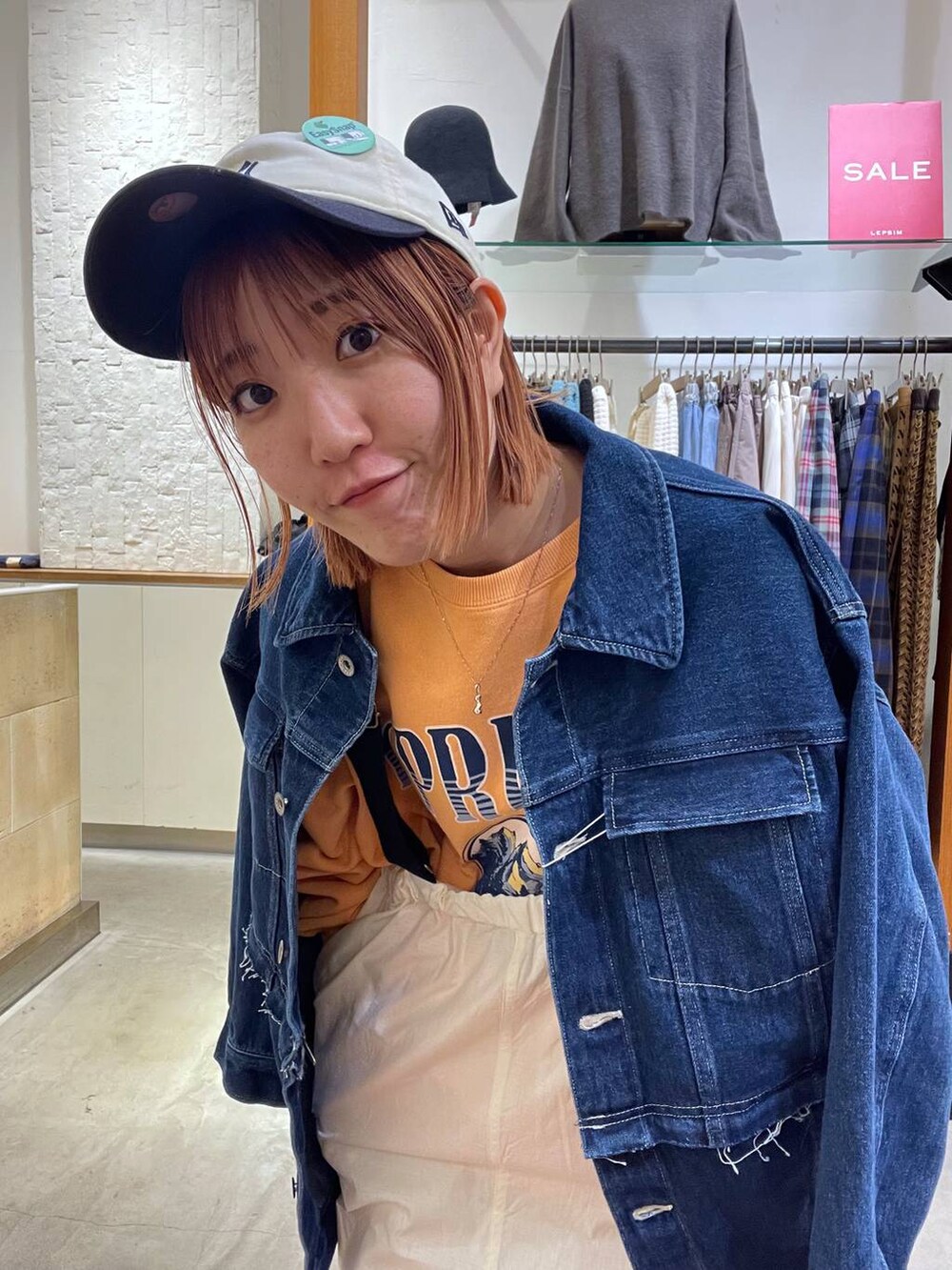 オレンジ系のスウェット、ブルー系のデニムジャケット、ホワイト系のスニーカーを着用したレディースの冬コーディネートの3枚目の写真