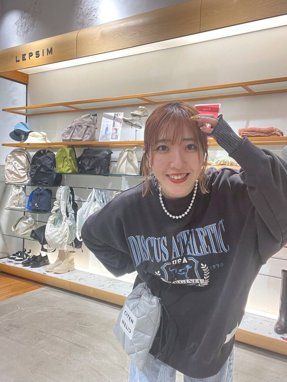 グレー系のスウェット、ブルー系のデニムパンツを着用したレディースの冬コーディネートの4枚目の写真