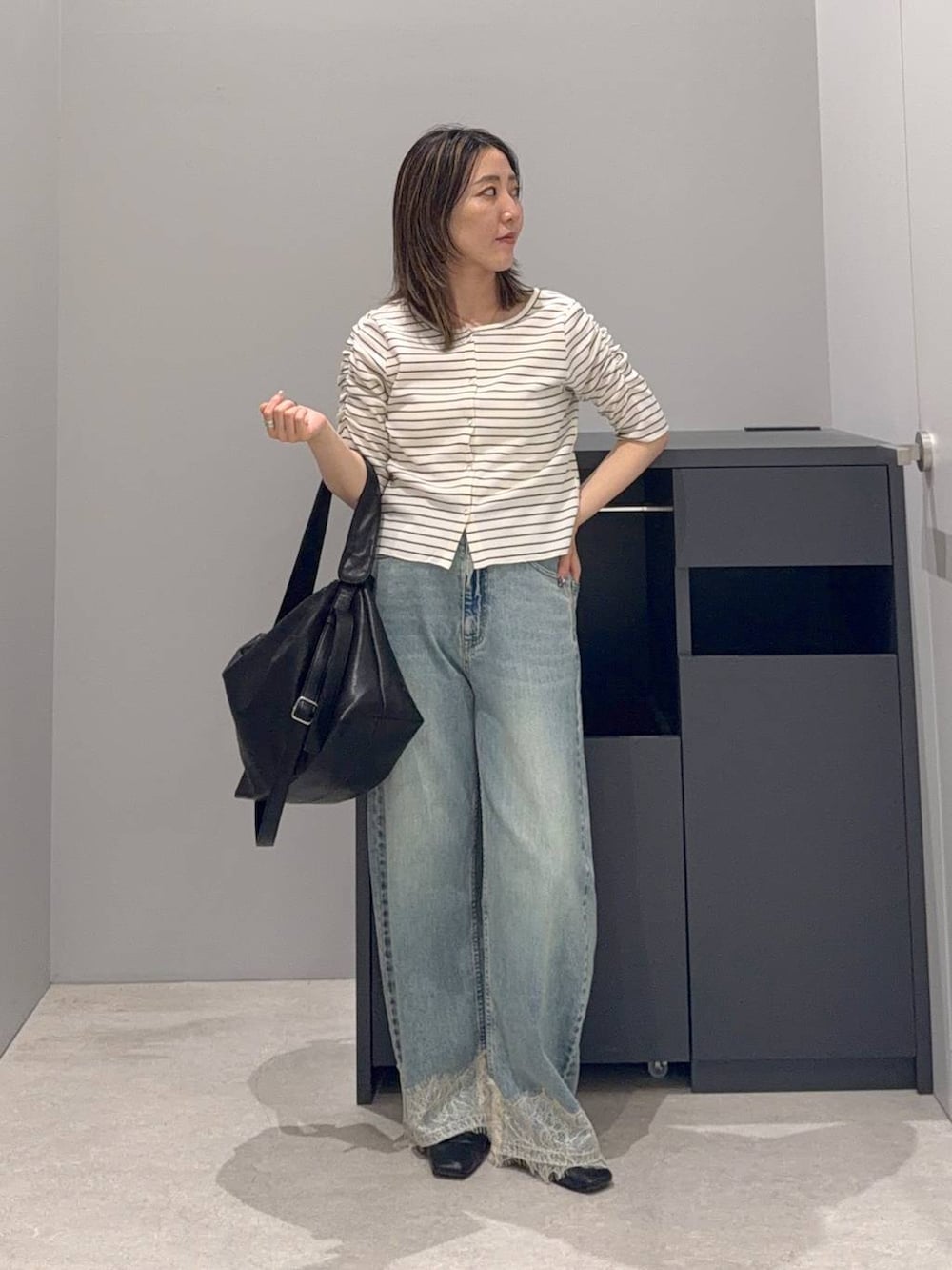 ブルー系のデニムパンツ、ブラック系のショルダーバッグ、ホワイト系のTシャツ/カットソーを着用したレディースの夏コーディネートの2枚目の写真