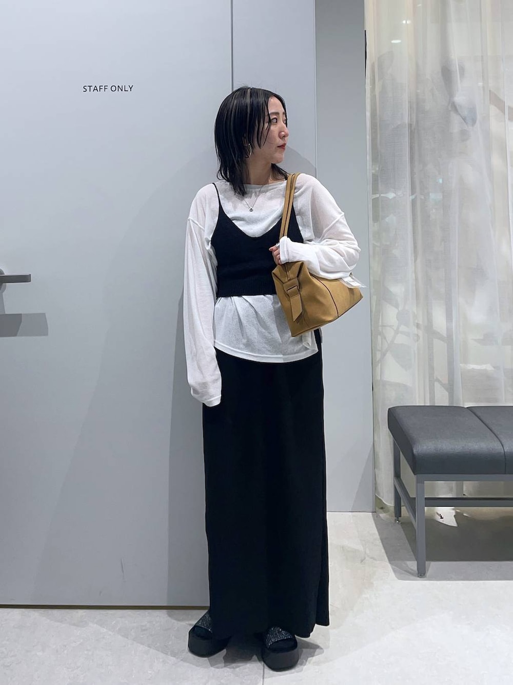 ブラック系のスカート、ベージュ系のボストンバッグ、ホワイト系のTシャツ/カットソーを着用したレディースの春コーディネートの2枚目の写真