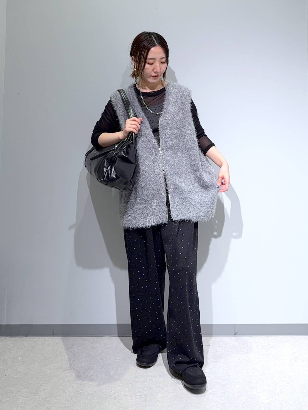 ブラック系のパンプス、ブラック系のトートバッグ、グレー系のベストを着用したレディースの秋コーディネートの3枚目の写真