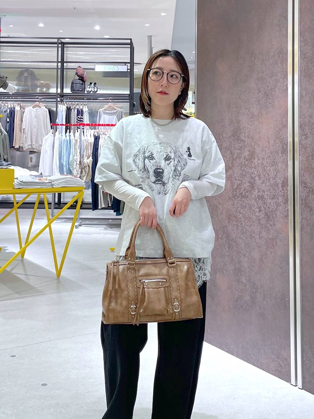 ホワイト系のキャミソール、ブラウン系のボストンバッグ、ブラック系のスウェットパンツを着用したレディースの春コーディネートの2枚目の写真