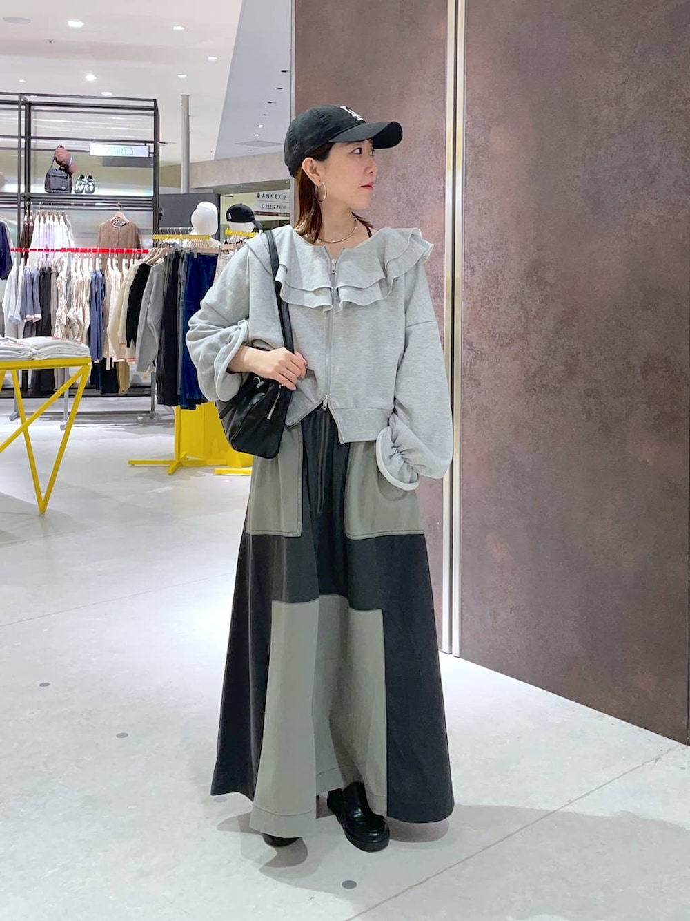 ブラック系のショルダーバッグ、グリーン系のスカートを着用したレディースの春コーディネートの2枚目の写真