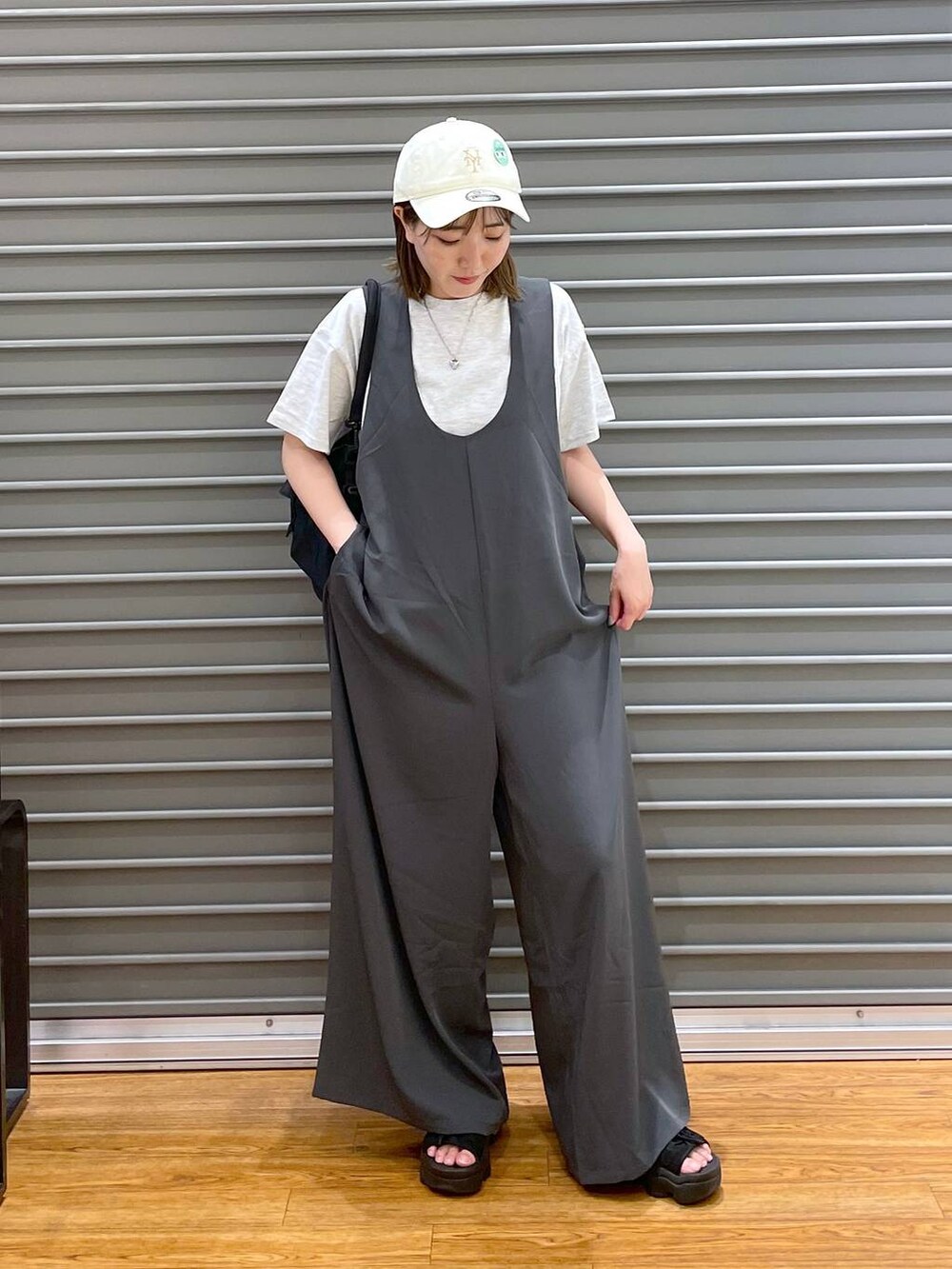 ブラック系のショルダーバッグ、ベージュ系のTシャツ/カットソー、グレー系のサロペット/オーバーオールを着用したレディースの夏コーディネートの2枚目の写真