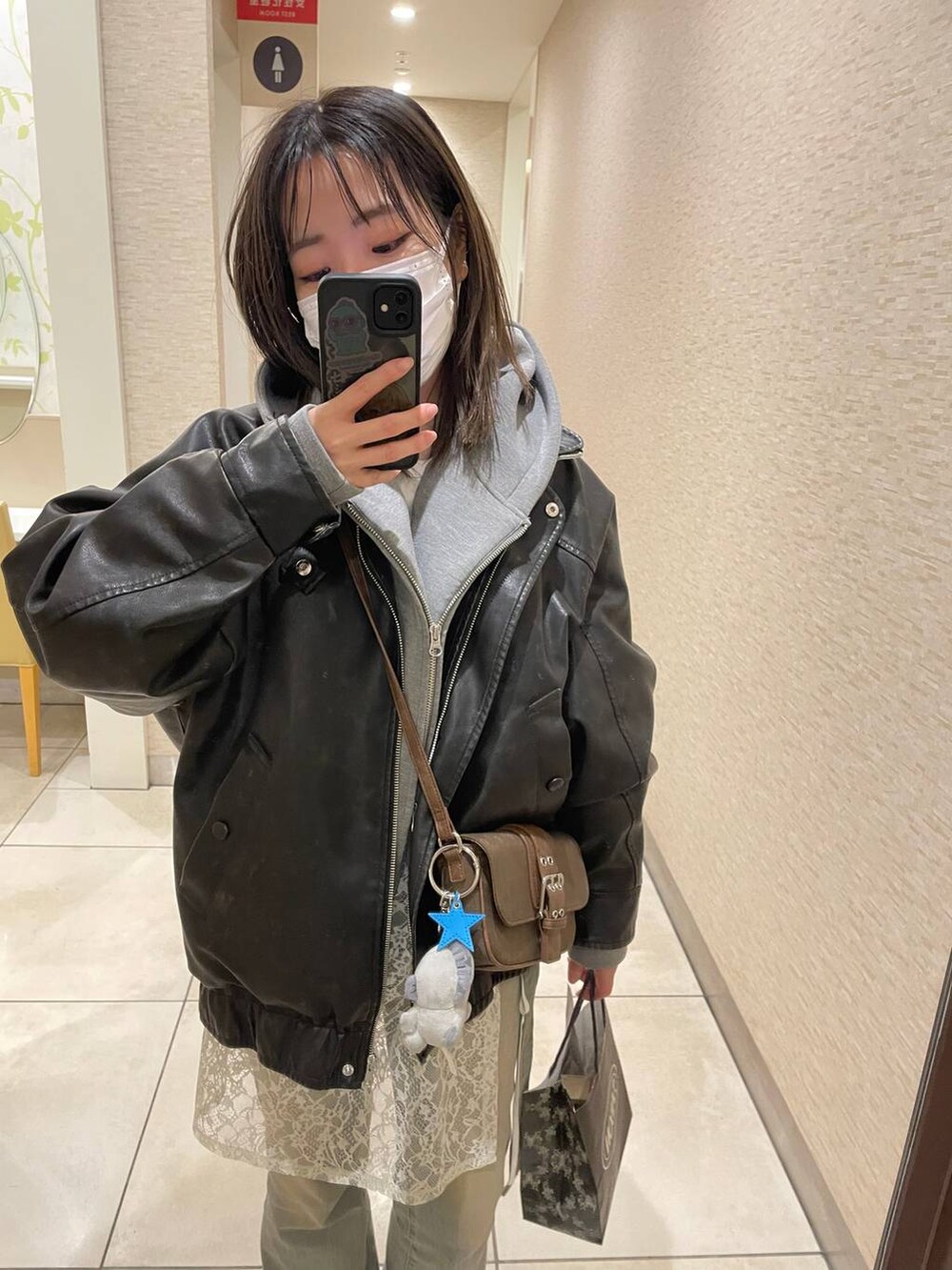 グリーン系のショルダーバッグ、ブルー系のデニムパンツ、ブルー系のキーホルダーを着用したレディースの春コーディネートの2枚目の写真
