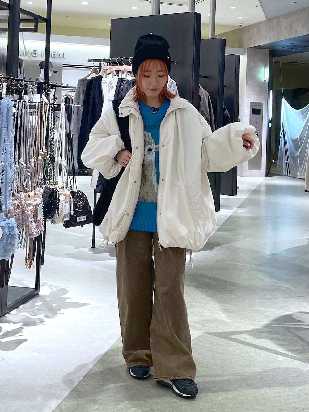 ホワイト系のその他アウター、ブラウン系のデニムパンツ、ブラック系のショルダーバッグを着用したレディースの冬コーディネートの2枚目の写真