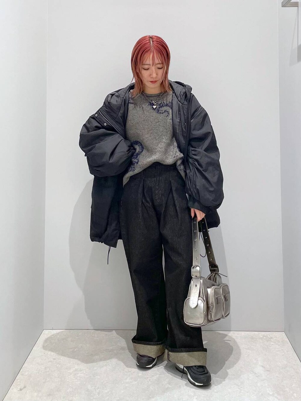 シルバー系のショルダーバッグ、ブラック系のブルゾン、ブラック系のデニムパンツを着用したレディースの秋コーディネートの2枚目の写真