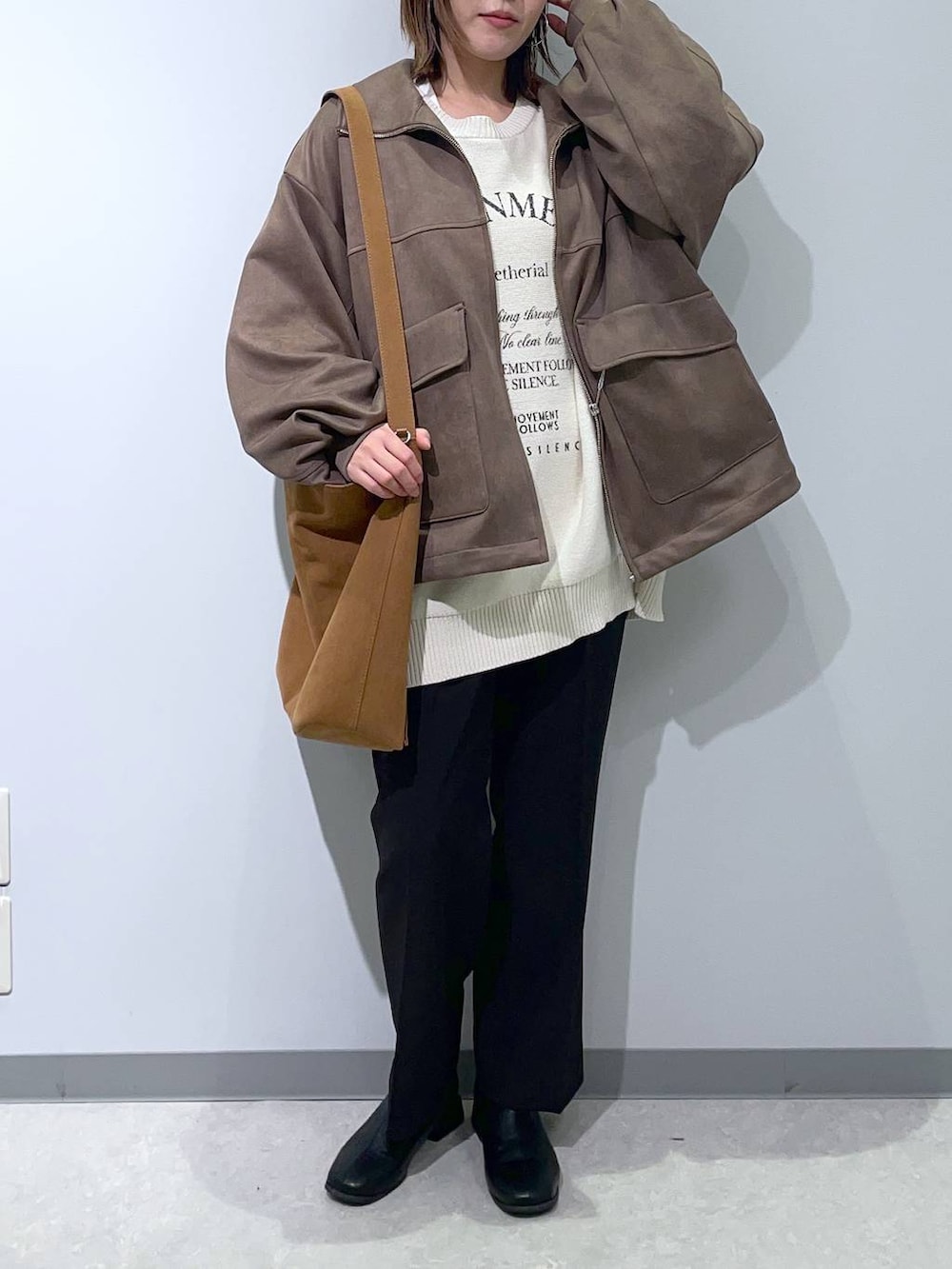 ブラック系のスラックス、ベージュ系のショルダーバッグ、ブラウン系のブルゾンを着用したレディースの秋コーディネートの2枚目の写真