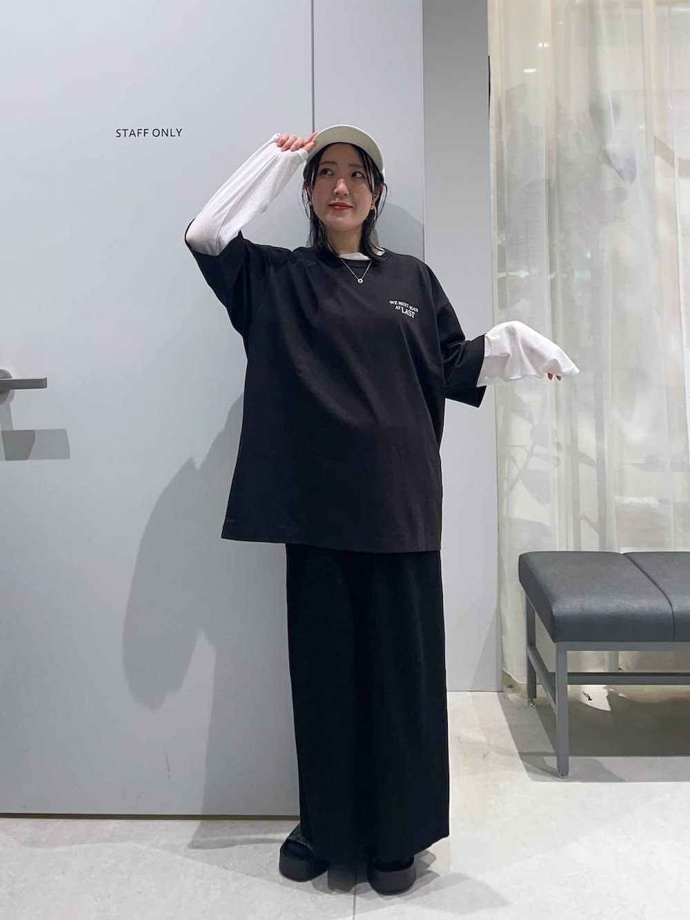 ブラック系のスカート、ホワイト系のTシャツ/カットソー、ブラック系のサンダルを着用したレディースの春コーディネートの2枚目の写真
