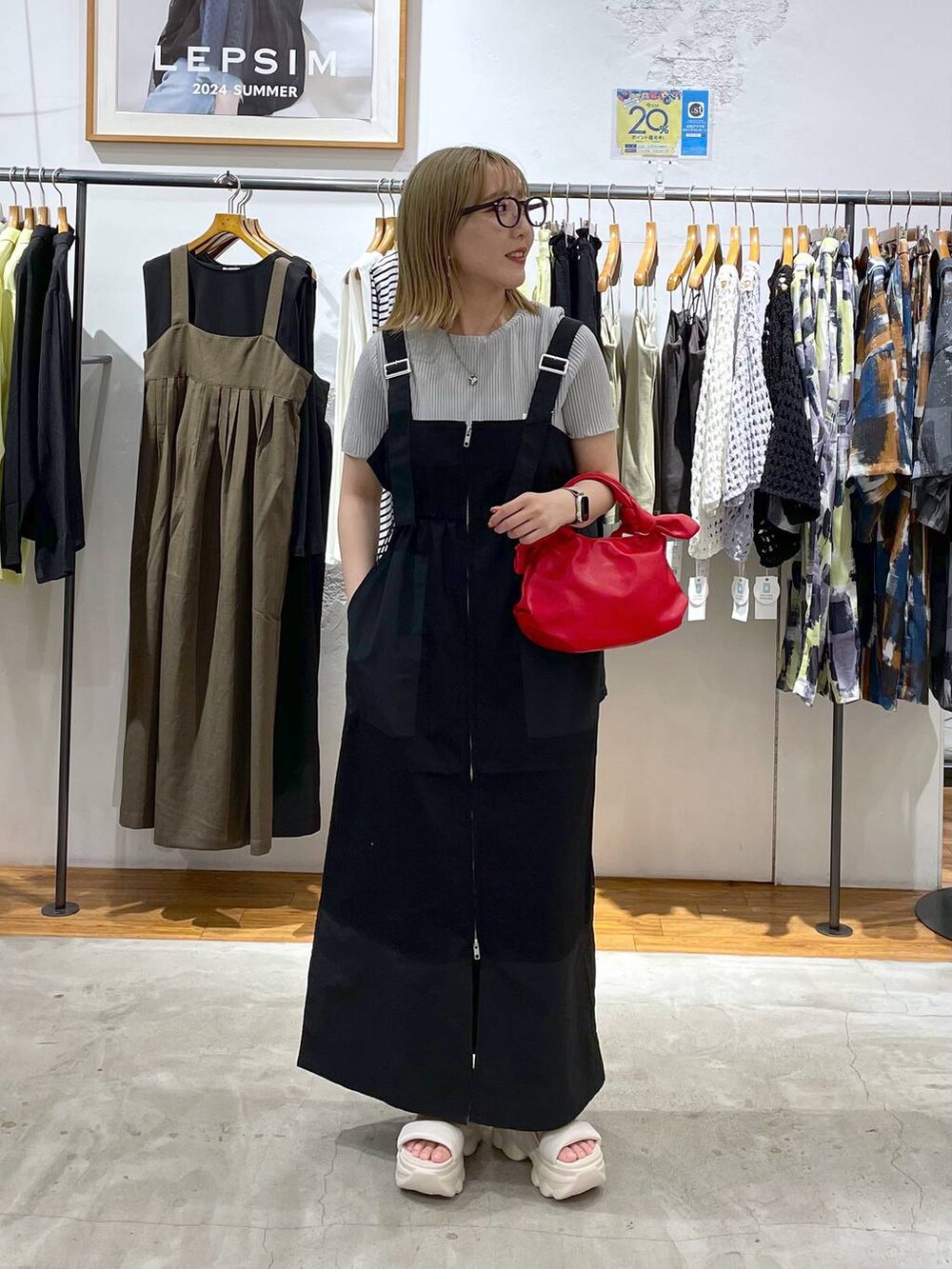 ホワイト系のサンダル、レッド系のショルダーバッグ、ブラック系のジャンパースカートを着用したレディースの夏コーディネートの3枚目の写真