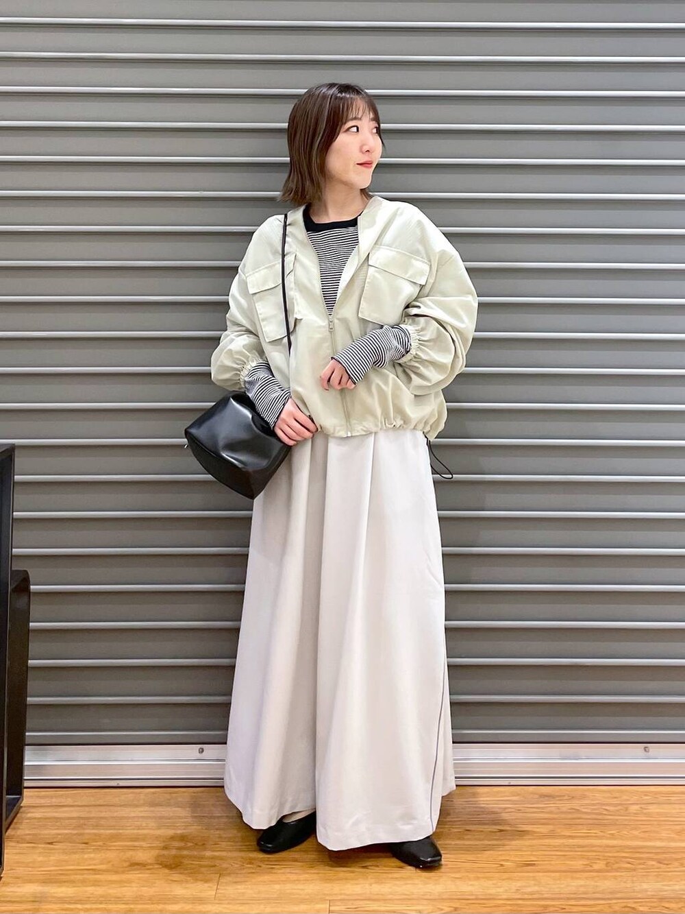 ブラック系のショルダーバッグ、ブラック系のパンプス、ホワイト系のTシャツ/カットソーを着用したレディースの春コーディネートの3枚目の写真