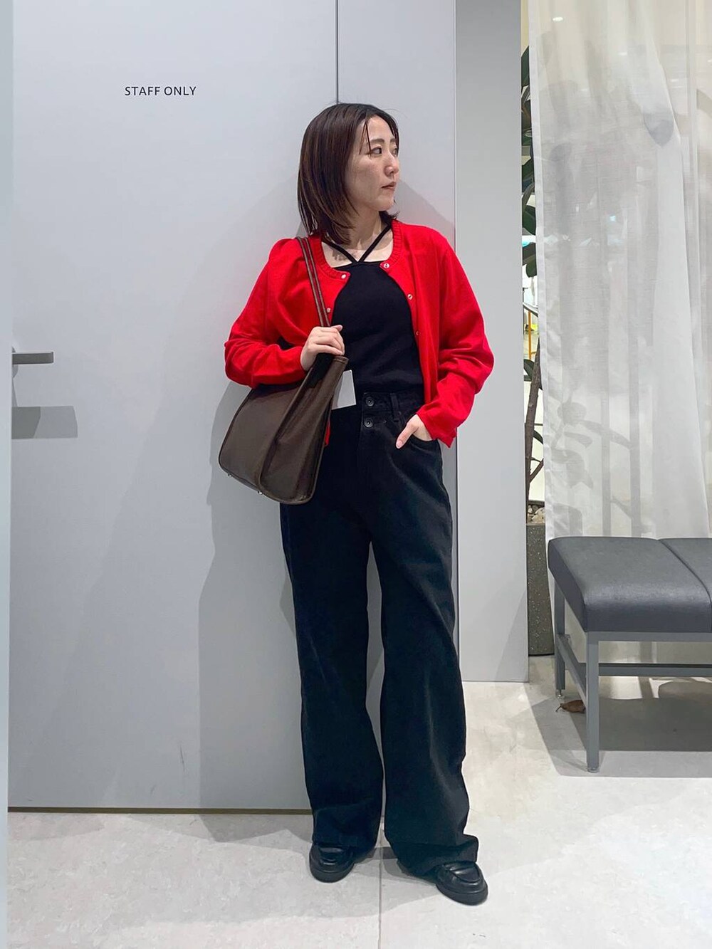 ブラウン系のトートバッグ、ブラック系のデニムパンツ、レッド系のカーディガン/ボレロを着用したレディースの春コーディネートの2枚目の写真