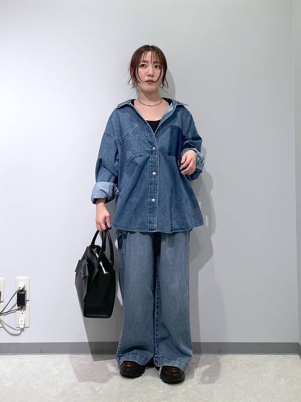 ブルー系のデニムパンツ、ブラック系のハンドバッグ、ブラウン系のローファーを着用したレディースの冬コーディネートの6枚目の写真